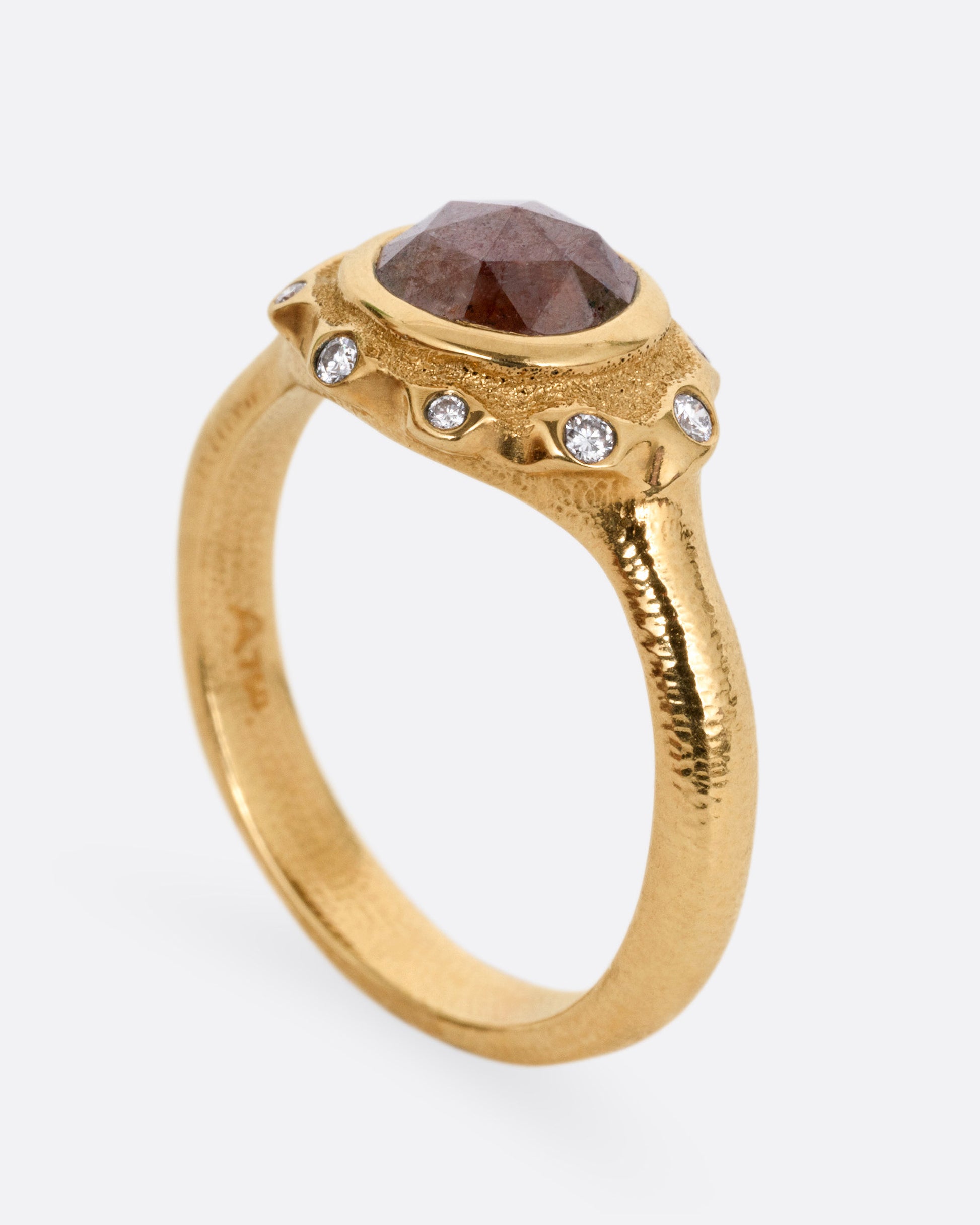 A yellow gold ring with a brown diamond and white diamond accents, shown from the side standing up.