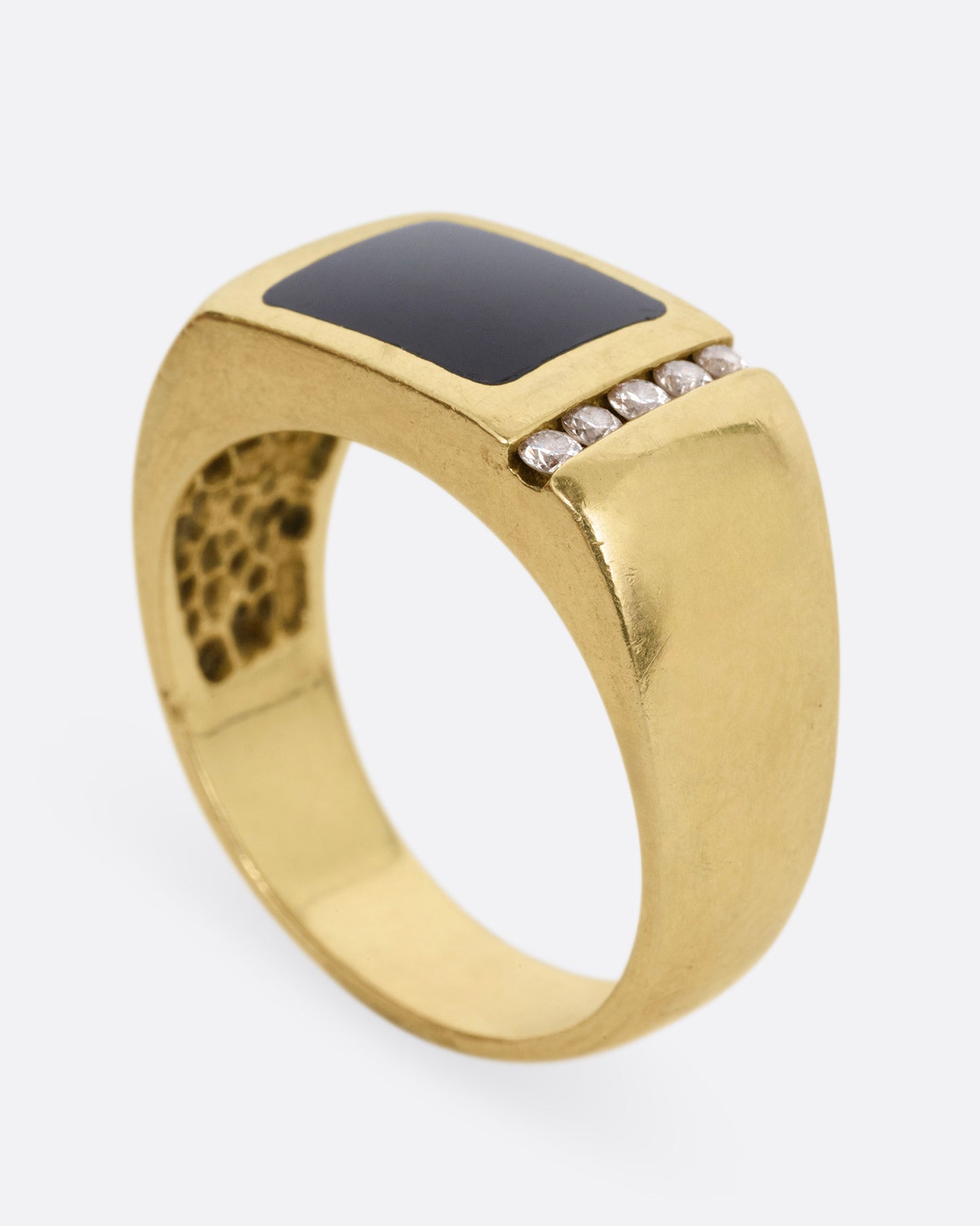 A yellow gold ring with a column of diamonds and a black enamel rectangle, shown from the side standing up.