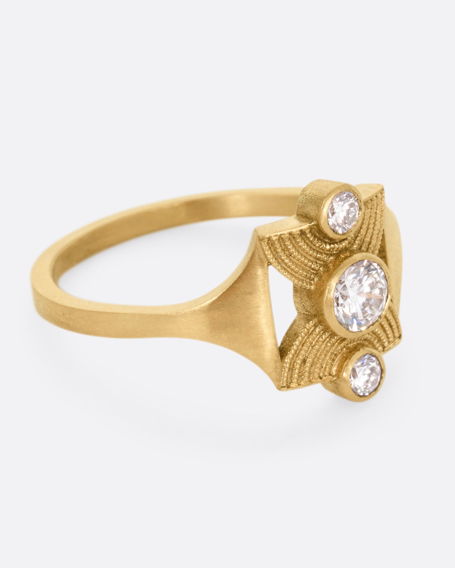 A yellow gold ring with an hourglass shape and three bezel set diamonds, shown from the side.
