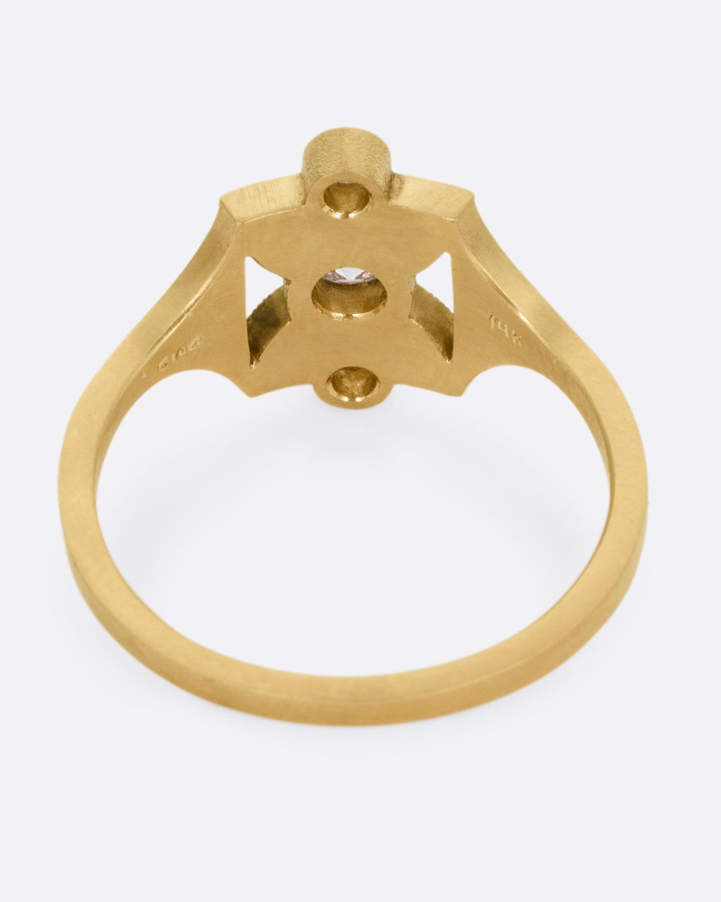 A yellow gold ring with an hourglass shape and three bezel set diamonds, shown from the back.