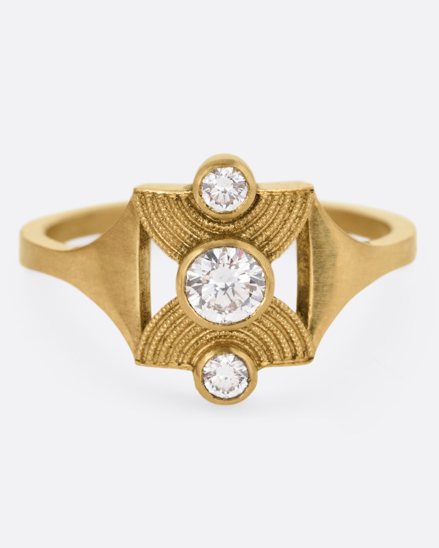 A yellow gold ring with an hourglass shape and three bezel set diamonds, shown from the front.