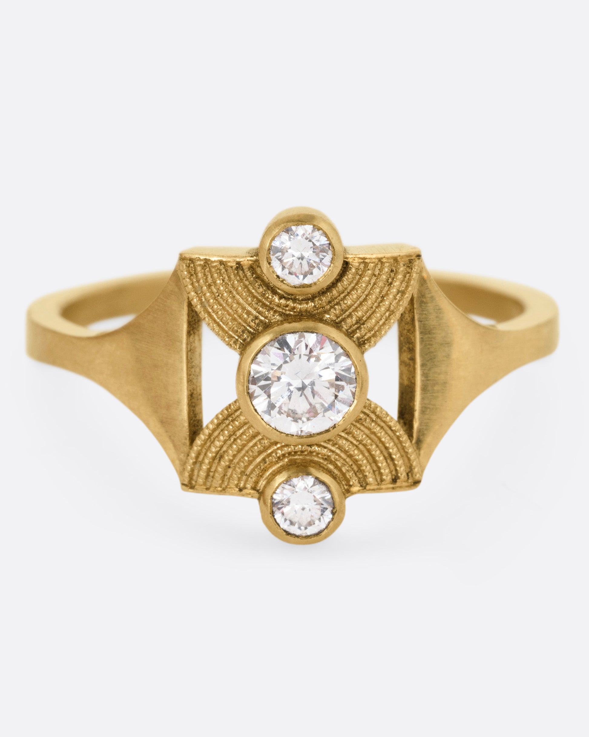 A yellow gold ring with an hourglass shape and three bezel set diamonds, shown from the front.
