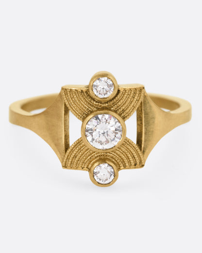 A yellow gold ring with an hourglass shape and three bezel set diamonds, shown from the front.