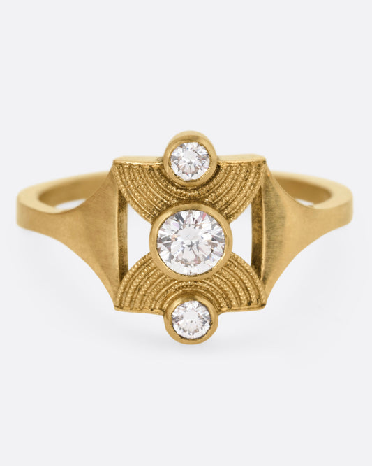 A yellow gold ring with an hourglass shape and three bezel set diamonds, shown from the front.