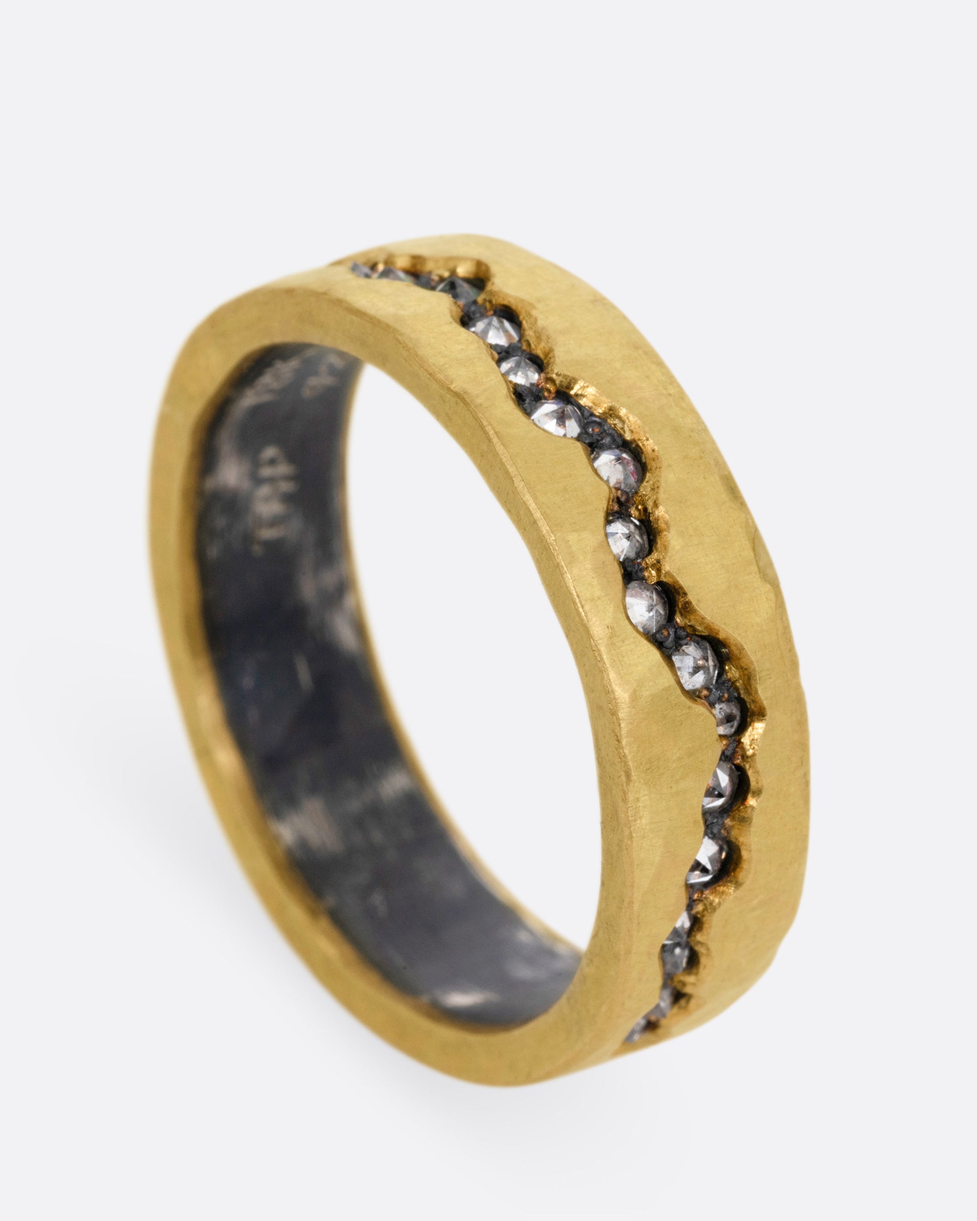 An oxidized silver ring with a yellow gold hammered finish and a fissure filled with inverted diamonds, shown standing up from the side.