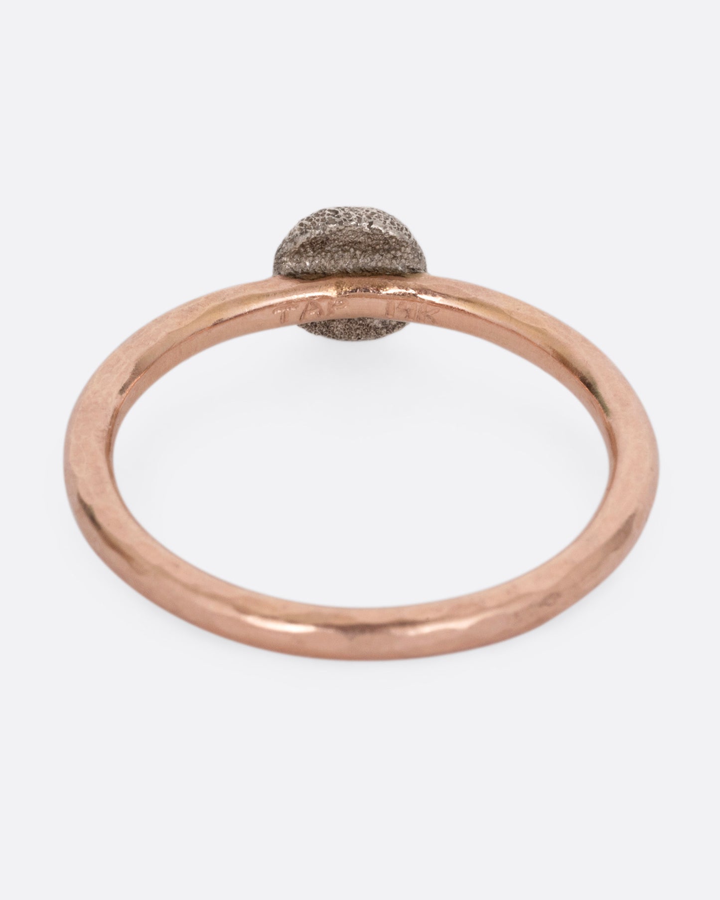 A rose gold ring with a diamond, shown from the back.