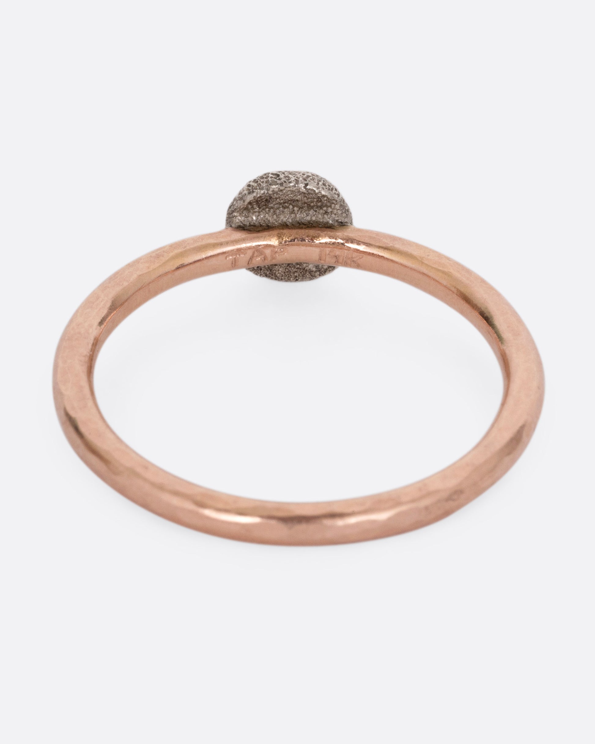 A rose gold ring with a diamond, shown from the back.