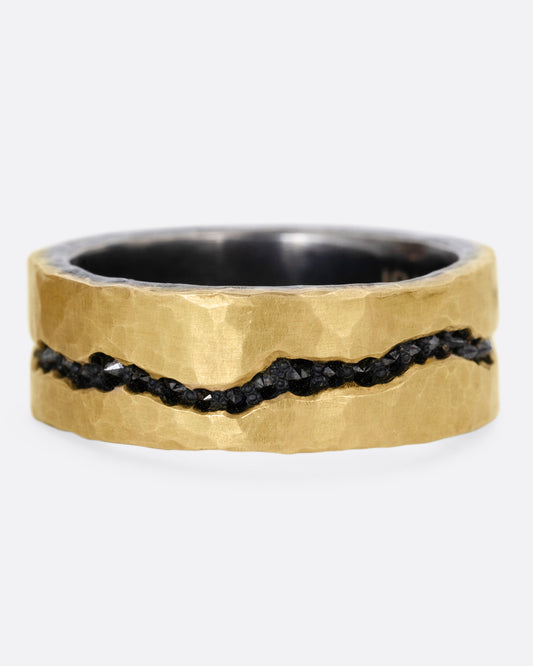 An oxidized silver ring with hammered yellow gold finish and a darkened fissure filled with inverted black diamonds, shown from the front.