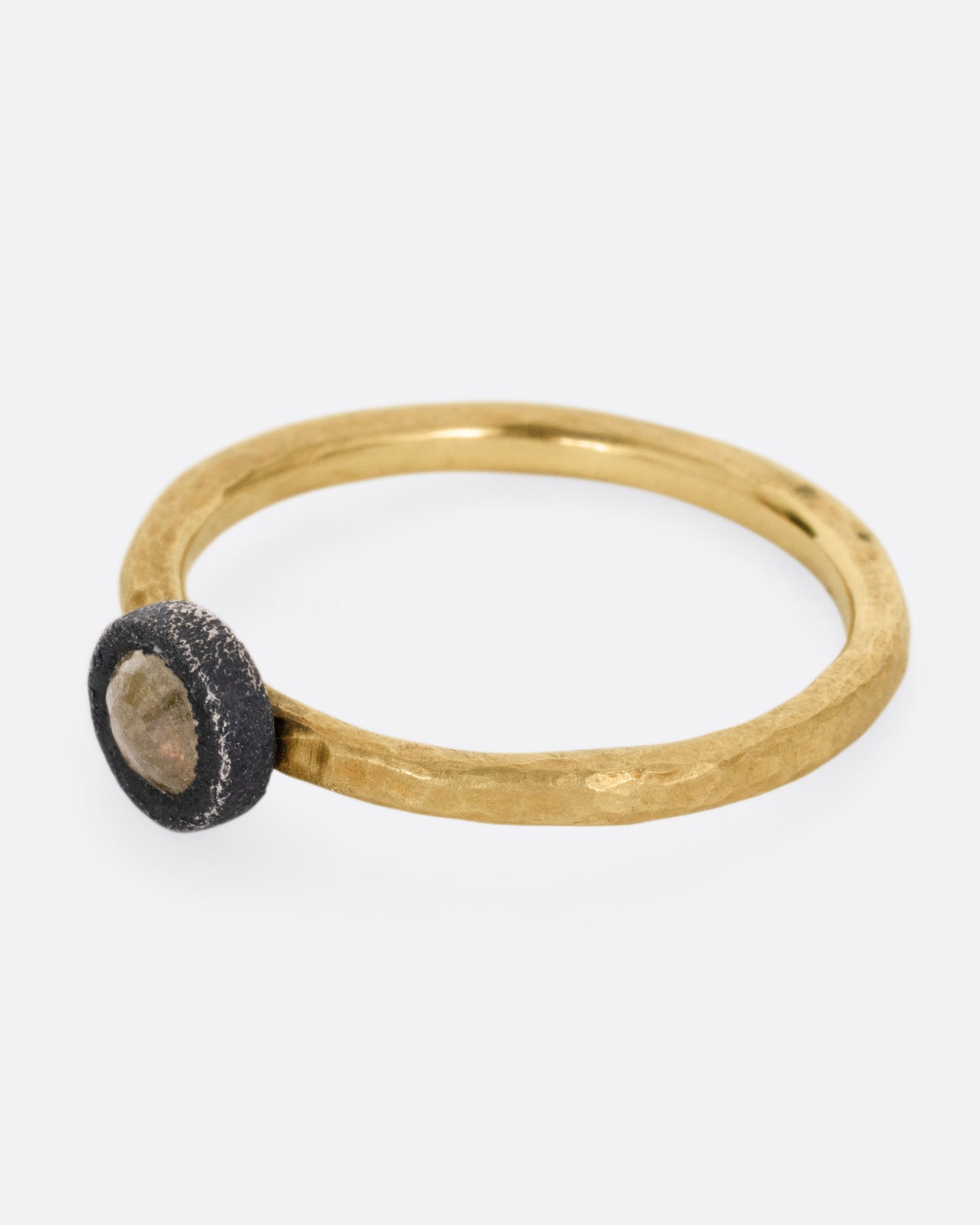 A yellow gold ring with a darkened sterling bezel and a yellow diamond, shown from the side.