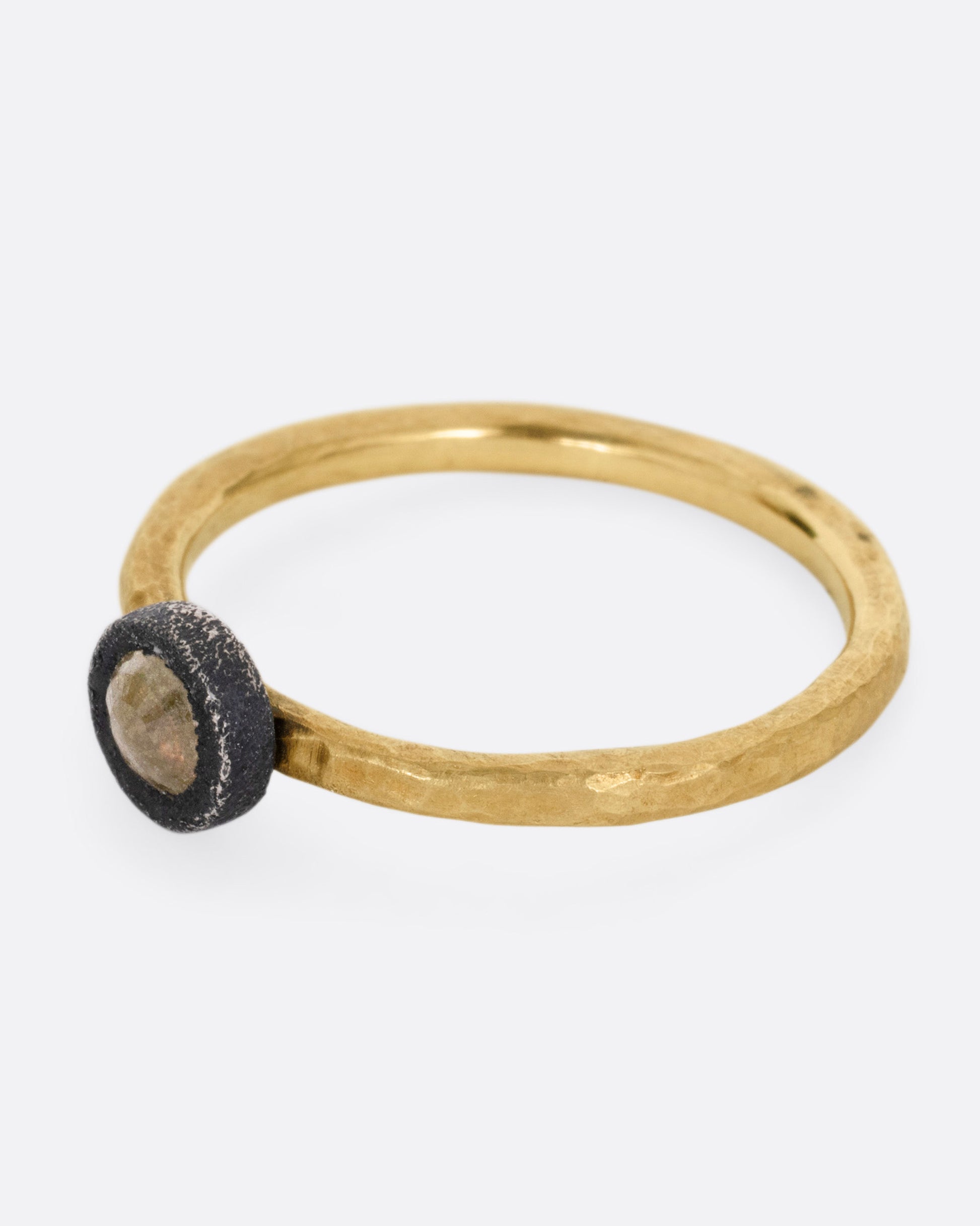 A yellow gold ring with a darkened sterling bezel and a yellow diamond, shown from the side.