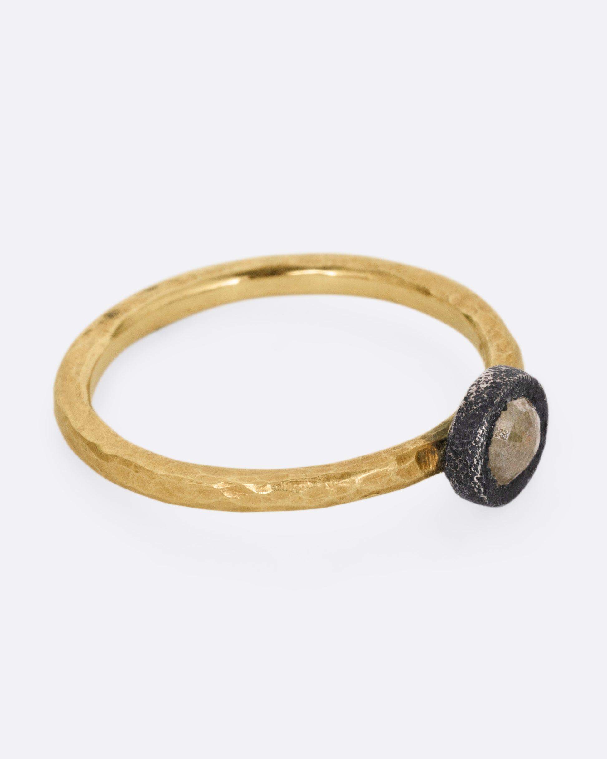 A yellow gold ring with a darkened sterling bezel and a yellow diamond, shown from the side.