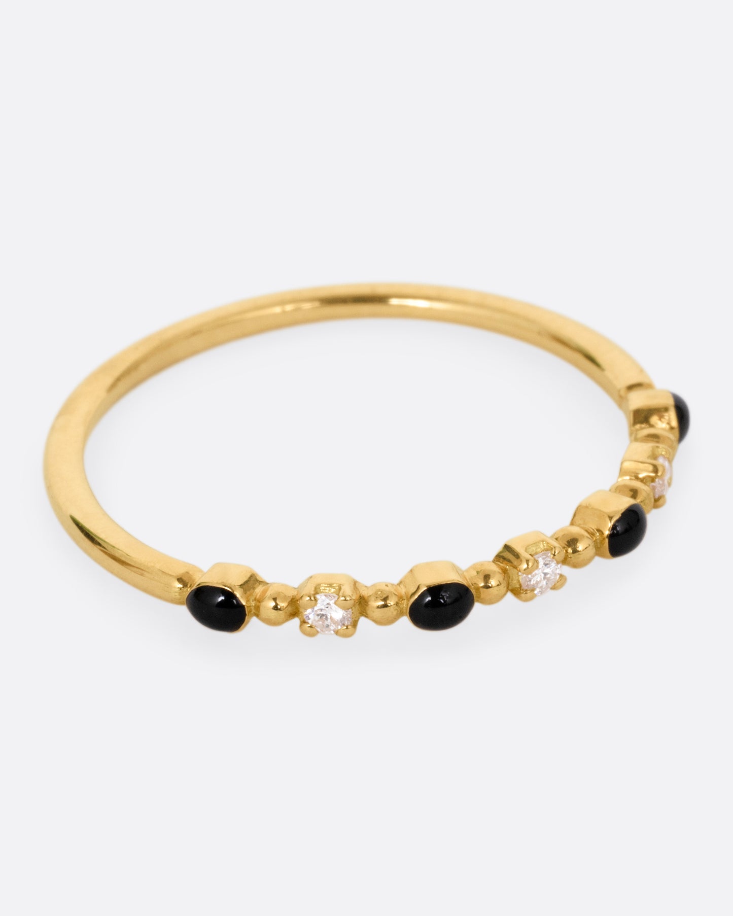 A yellow gold ring with three white diamonds and four black resin droplets, shown from the side.