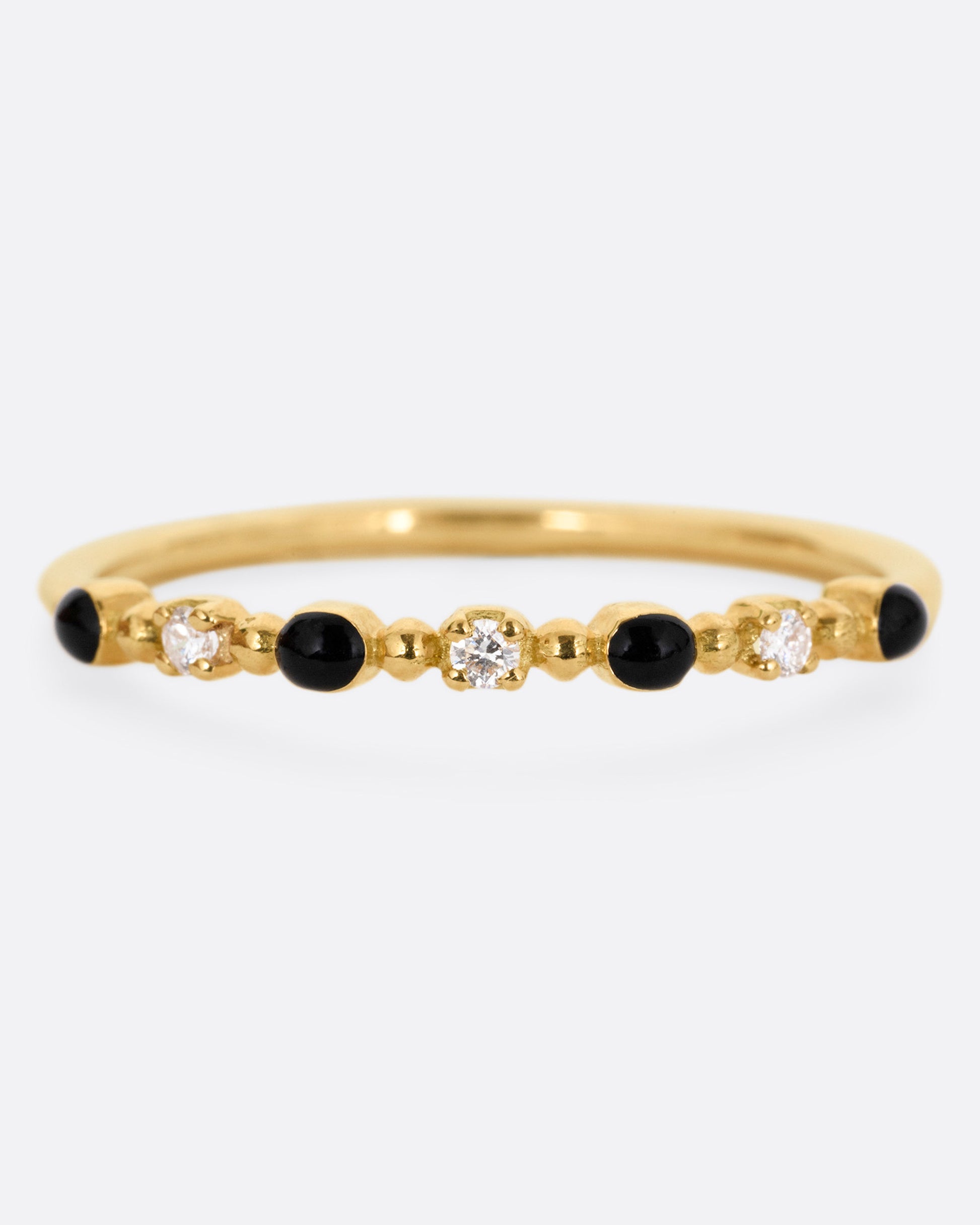 A yellow gold ring with three white diamonds and four black resin droplets, shown from the front.