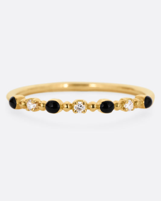 A yellow gold ring with three white diamonds and four black resin droplets, shown from the front.