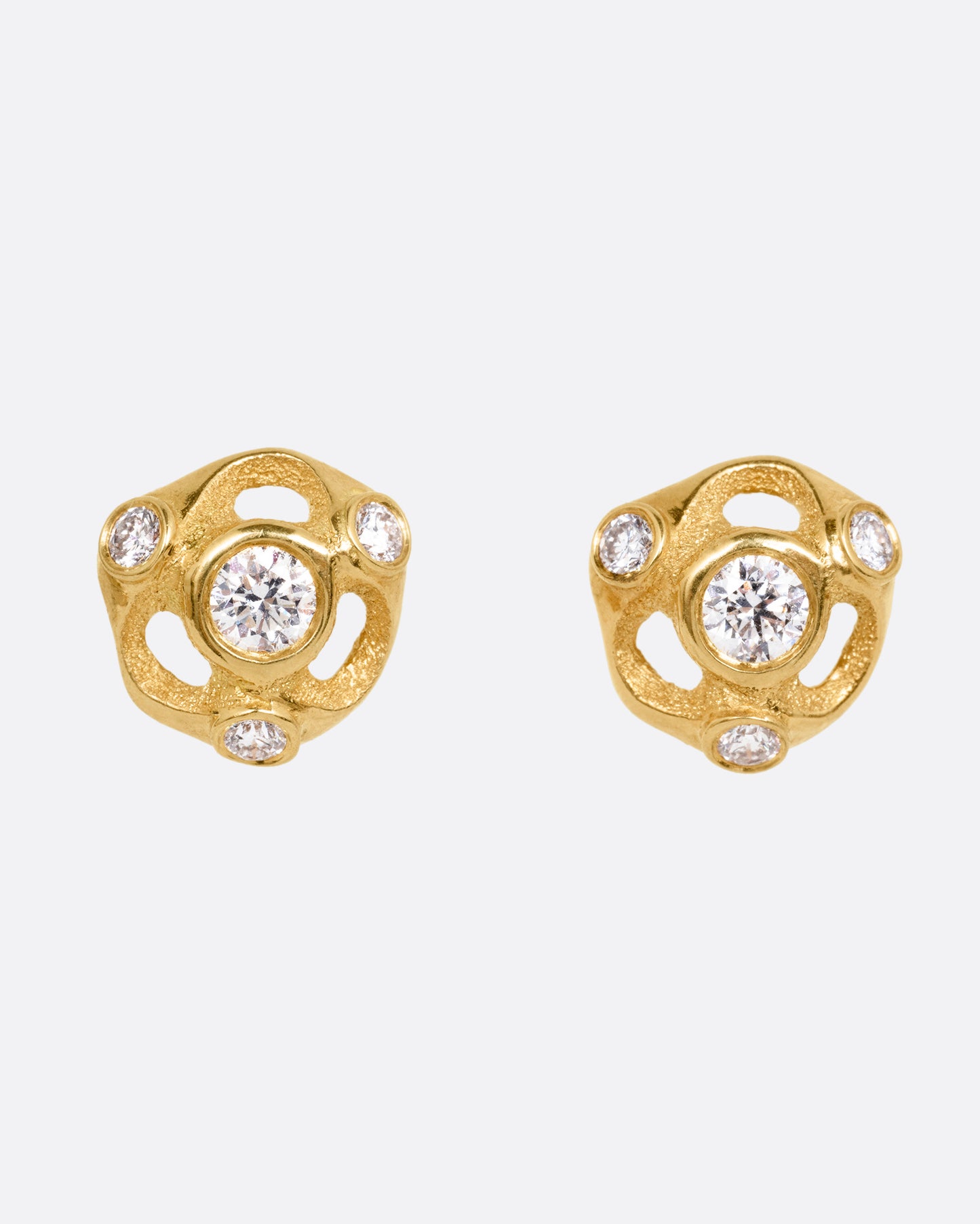 A pair of yellow gold stud earrings with four brilliant cut diamonds in each, shown from the front.
