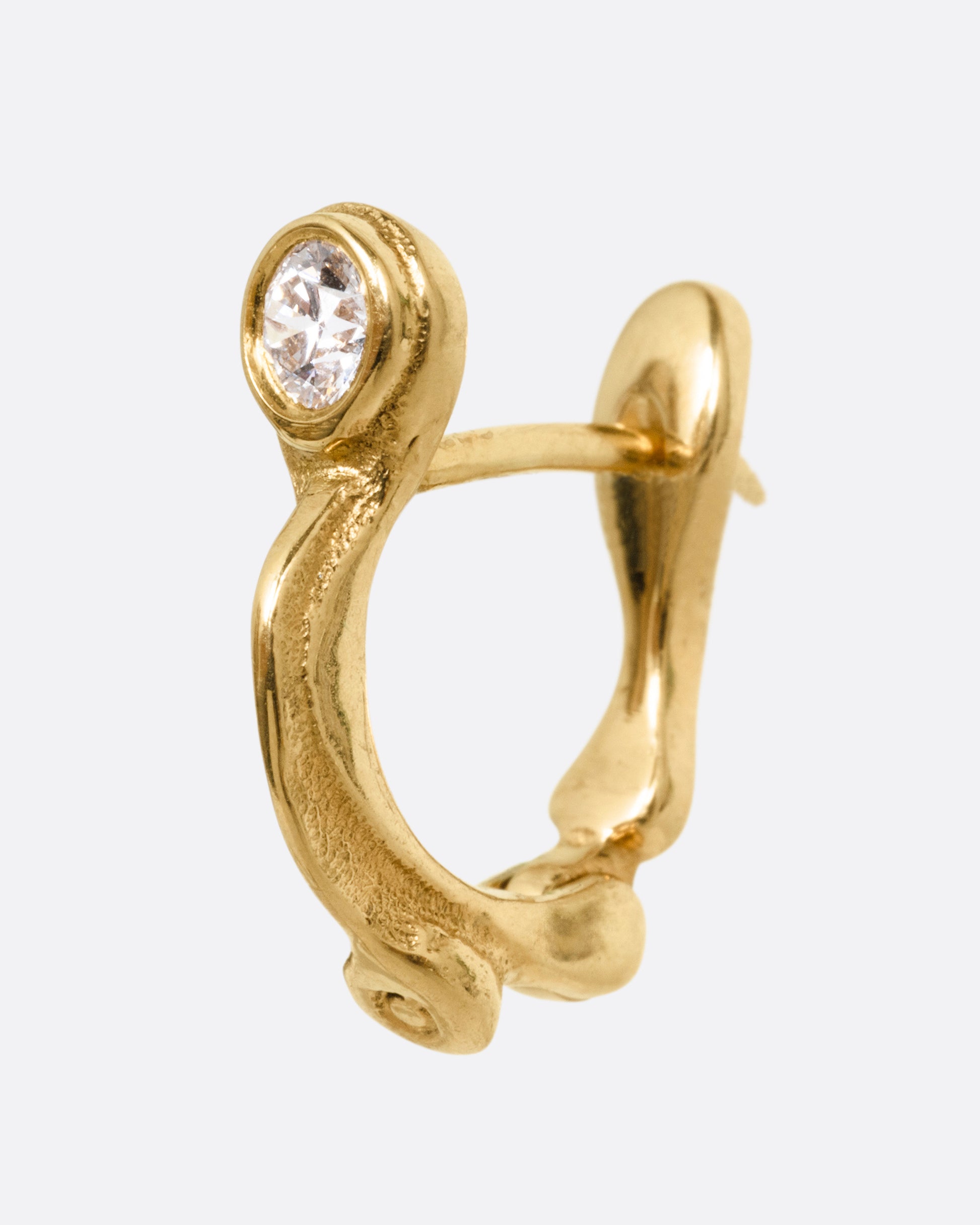 A yellow gold hoop earring with a brilliant cut diamond, shown from the side.