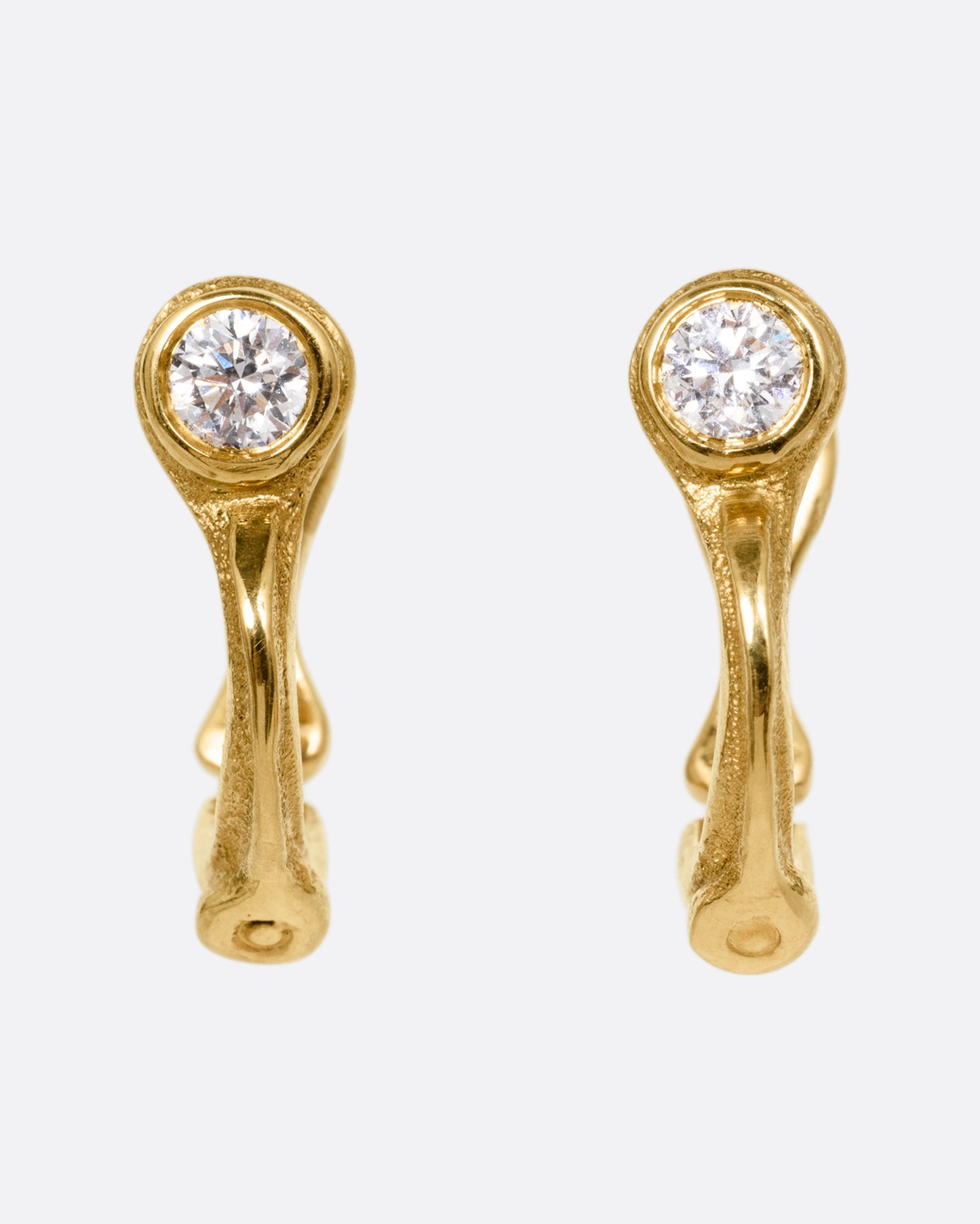 A pair of yellow gold hoop earring with brilliant cut diamonds, shown from the front.