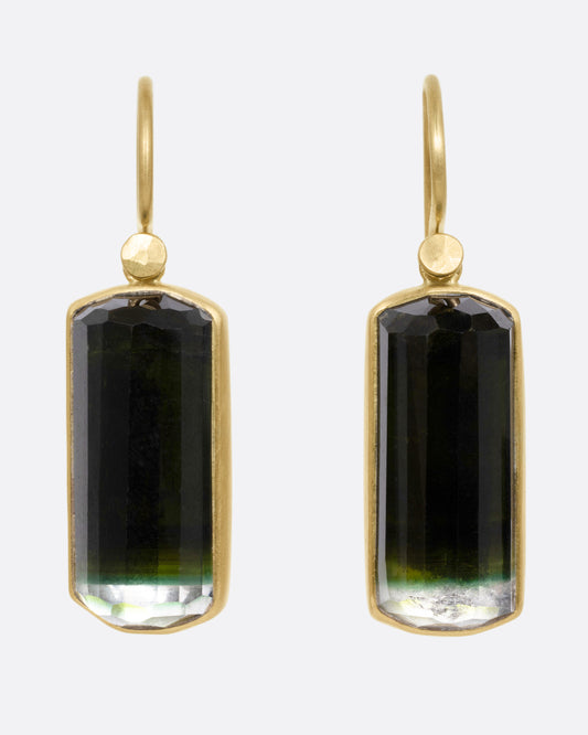 A pair of yellow gold drop earrings with bicolor barrel cut green tourmalines, shown from the front.