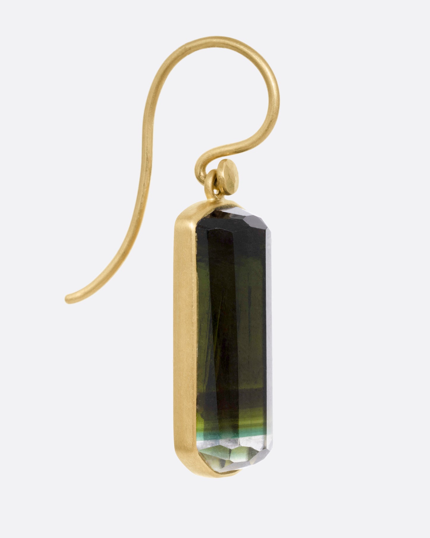 A yellow gold drop earrings with a bicolor barrel cut green tourmaline, shown from the side.