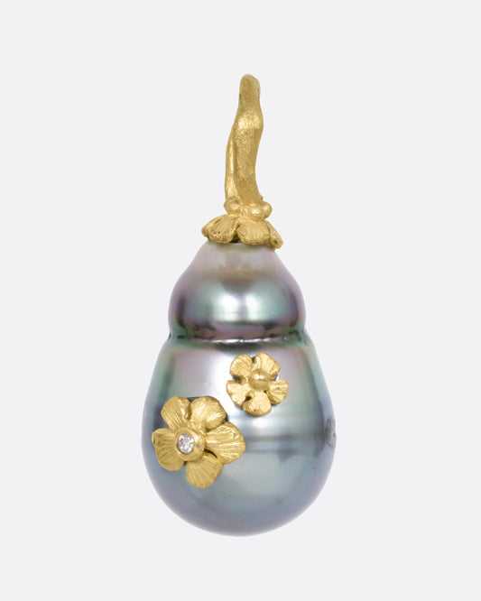 A yellow gold  Tahitian pearl pendant with diamond accented flower details, shown from the front.