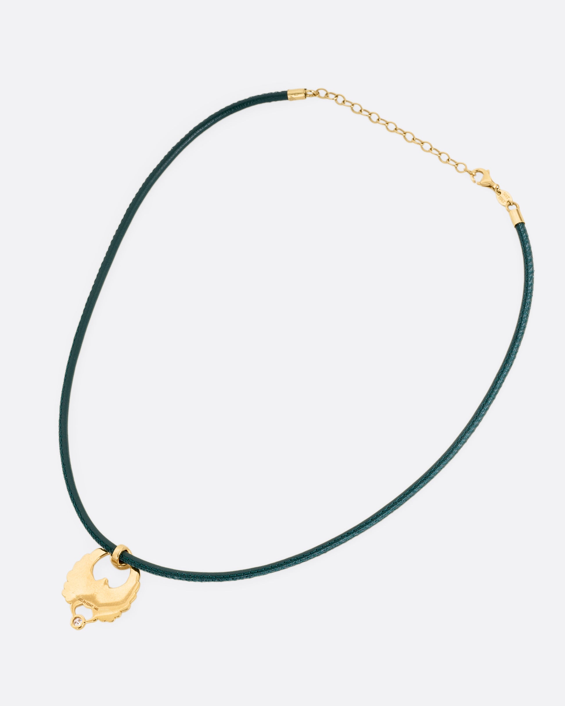 A yellow gold scarab pendant with a ruby and diamond, suspended from a green leather choker cord. Shown from the back.