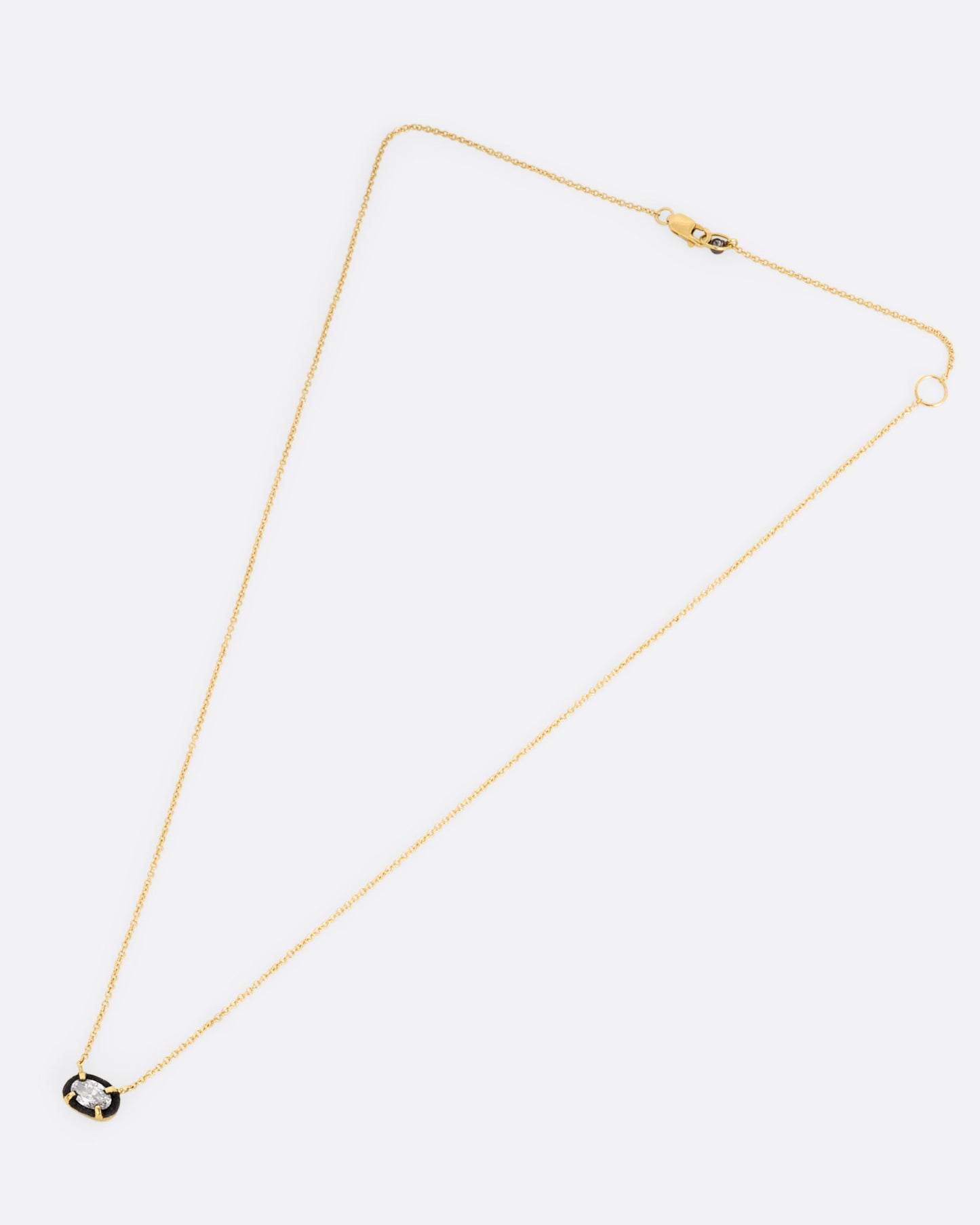 A yellow gold necklace with a pendant of darkened white gold surrounding a prong set diamond, shown from the front.