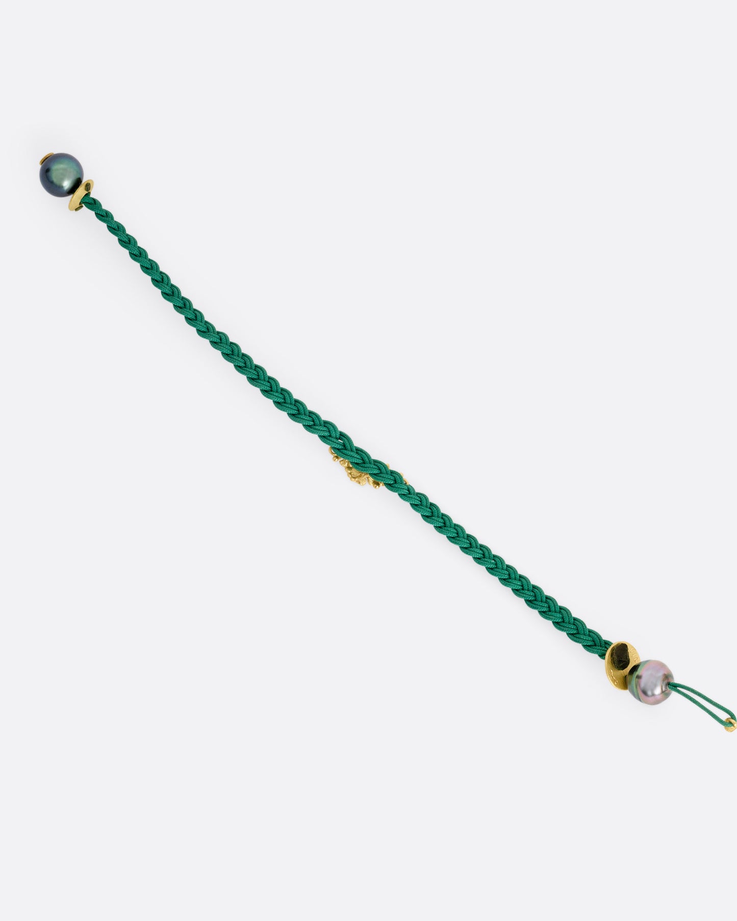 A braided green cord bracelet with a yellow gold cluster of diamond accented flowers and a Tahitian pearl toggle closure. Shown from the back open.