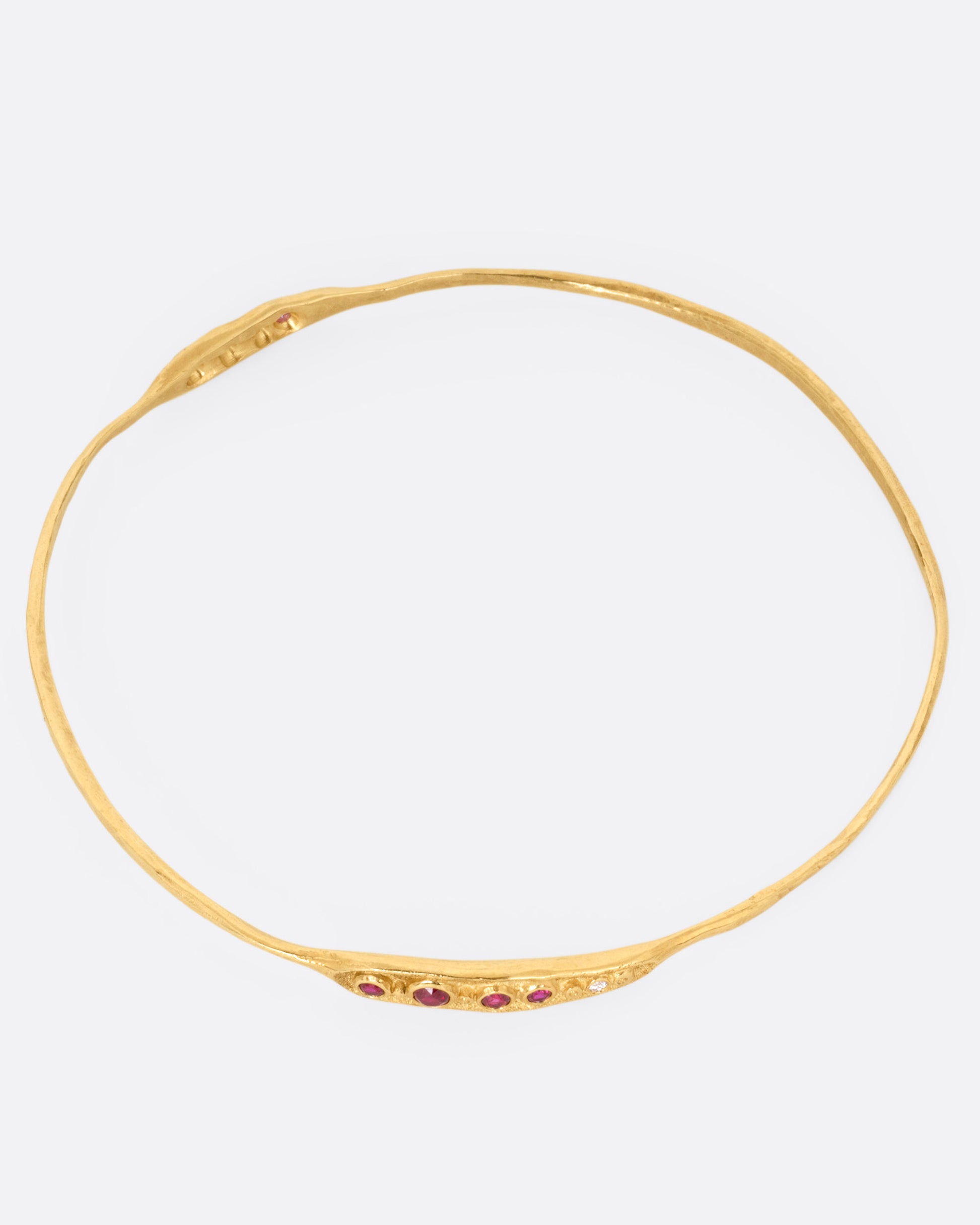 A yellow gold bracelet with rubies and diamonds, shown from the top.