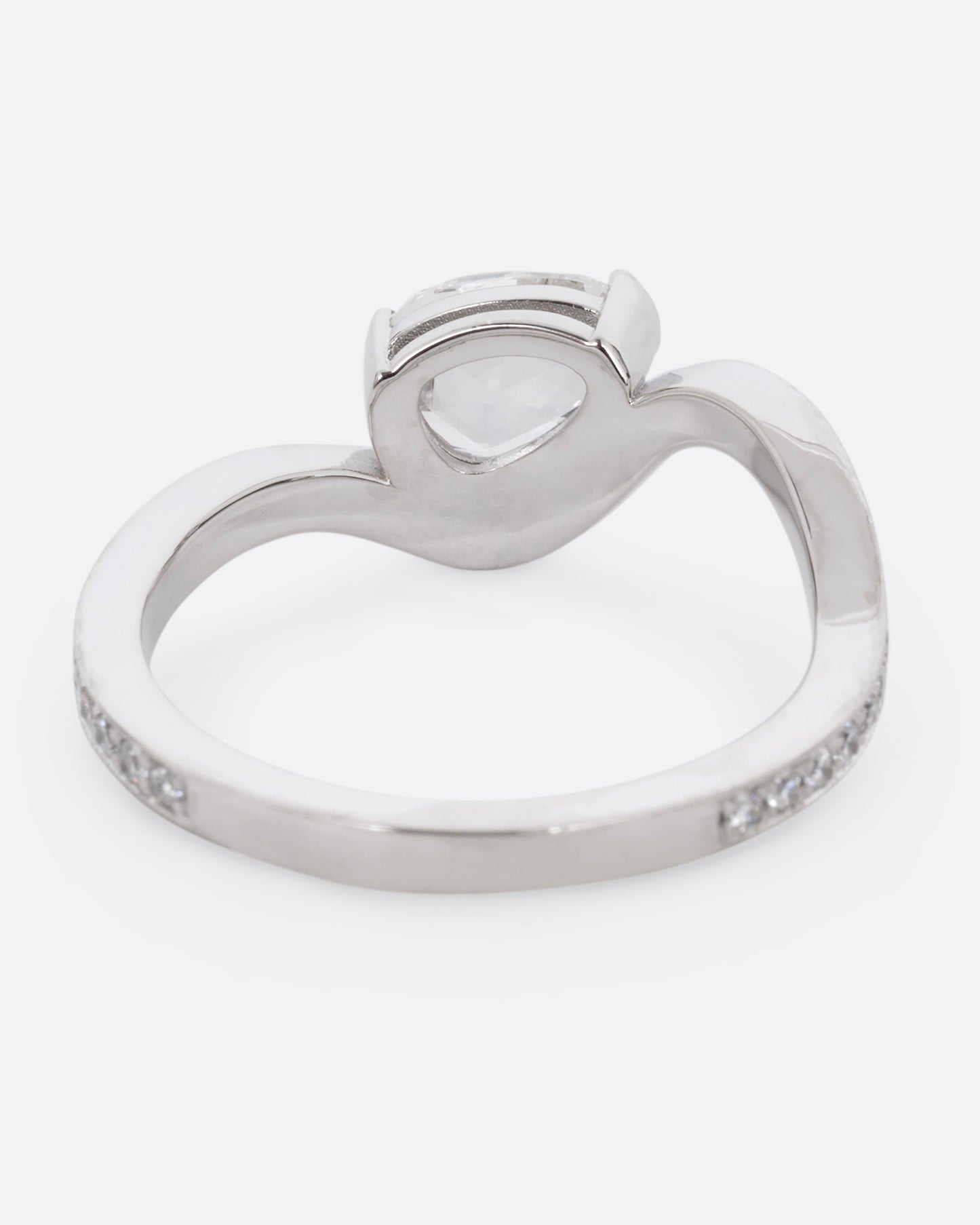 A diamond studded platinum ring with a wavy silhouette and a pear shaped rose cut diamond, shown from the back. 