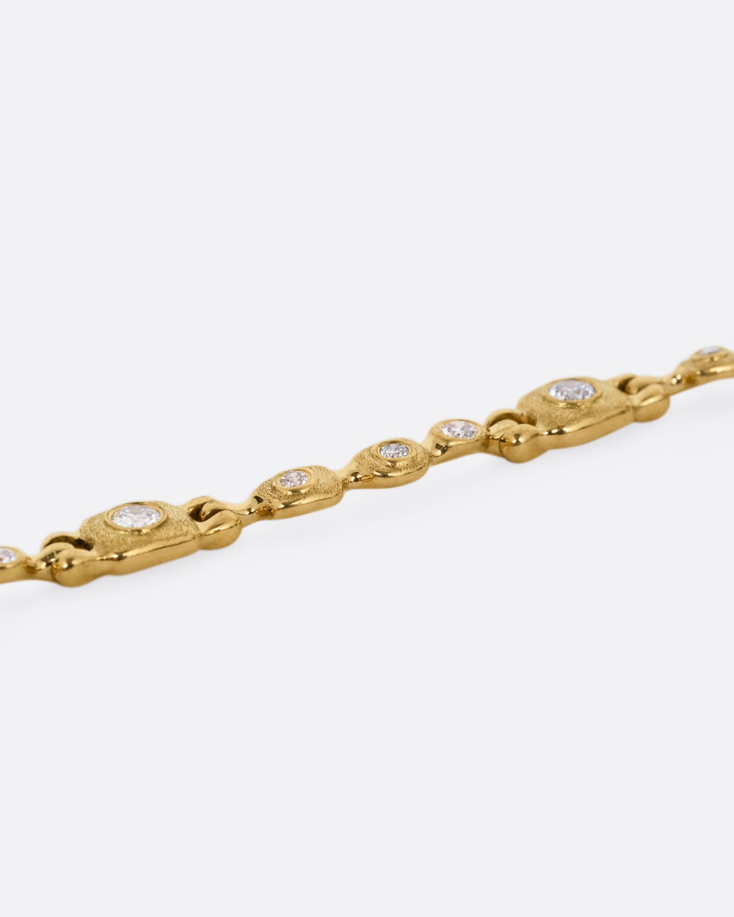 A yellow gold linked necklace with diamonds, shown from the side.