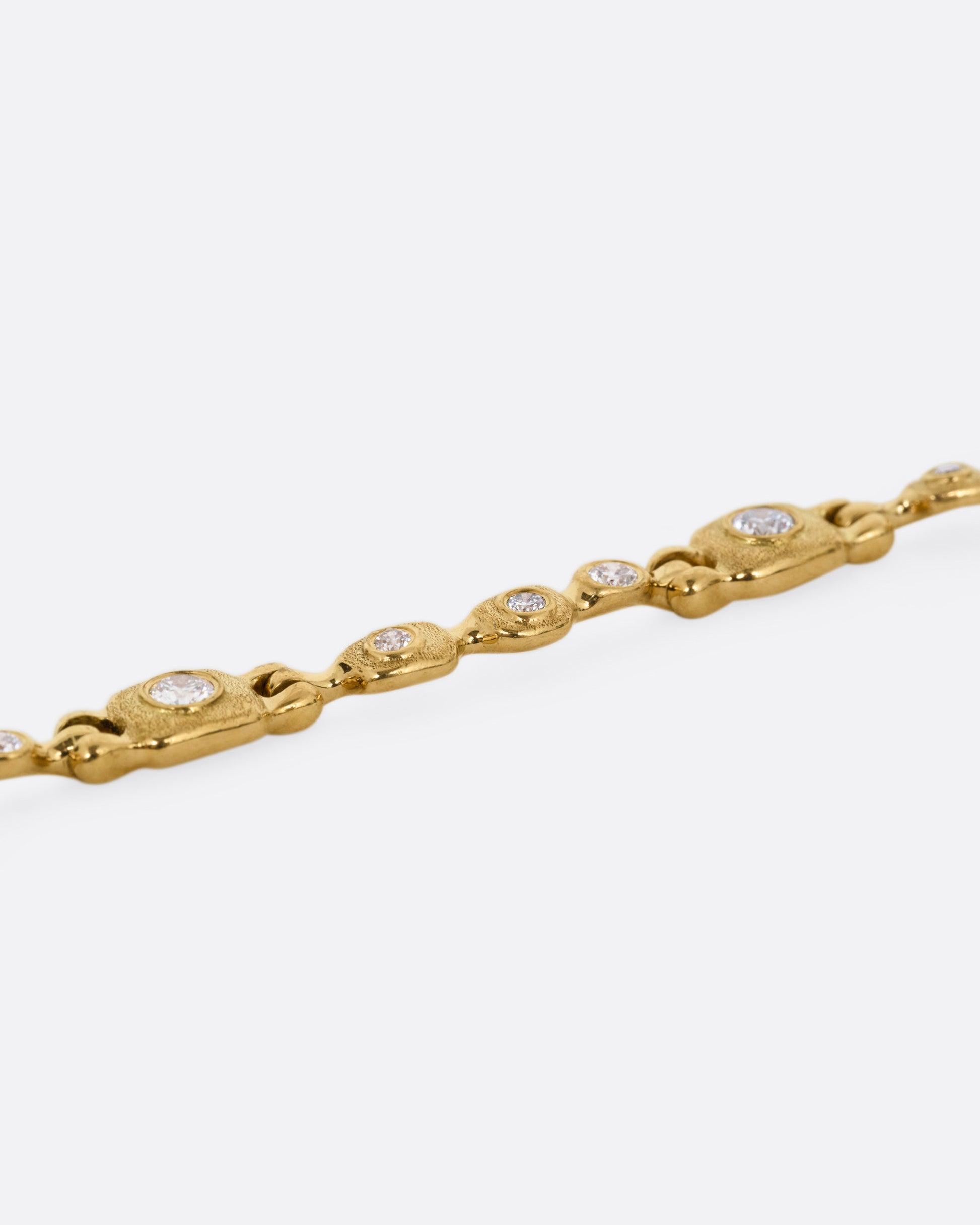 A yellow gold linked necklace with diamonds, shown from the side.