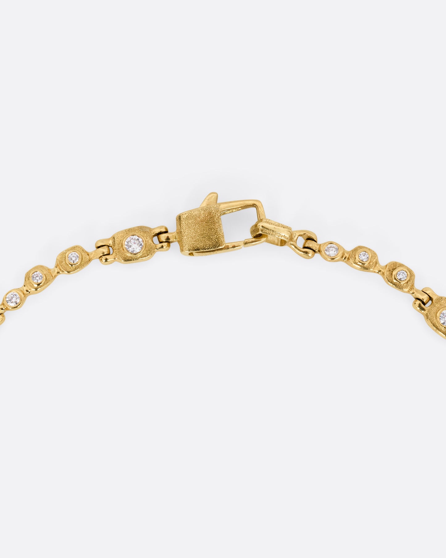 A close up of a yellow gold linked necklace with diamonds, shown from the front.