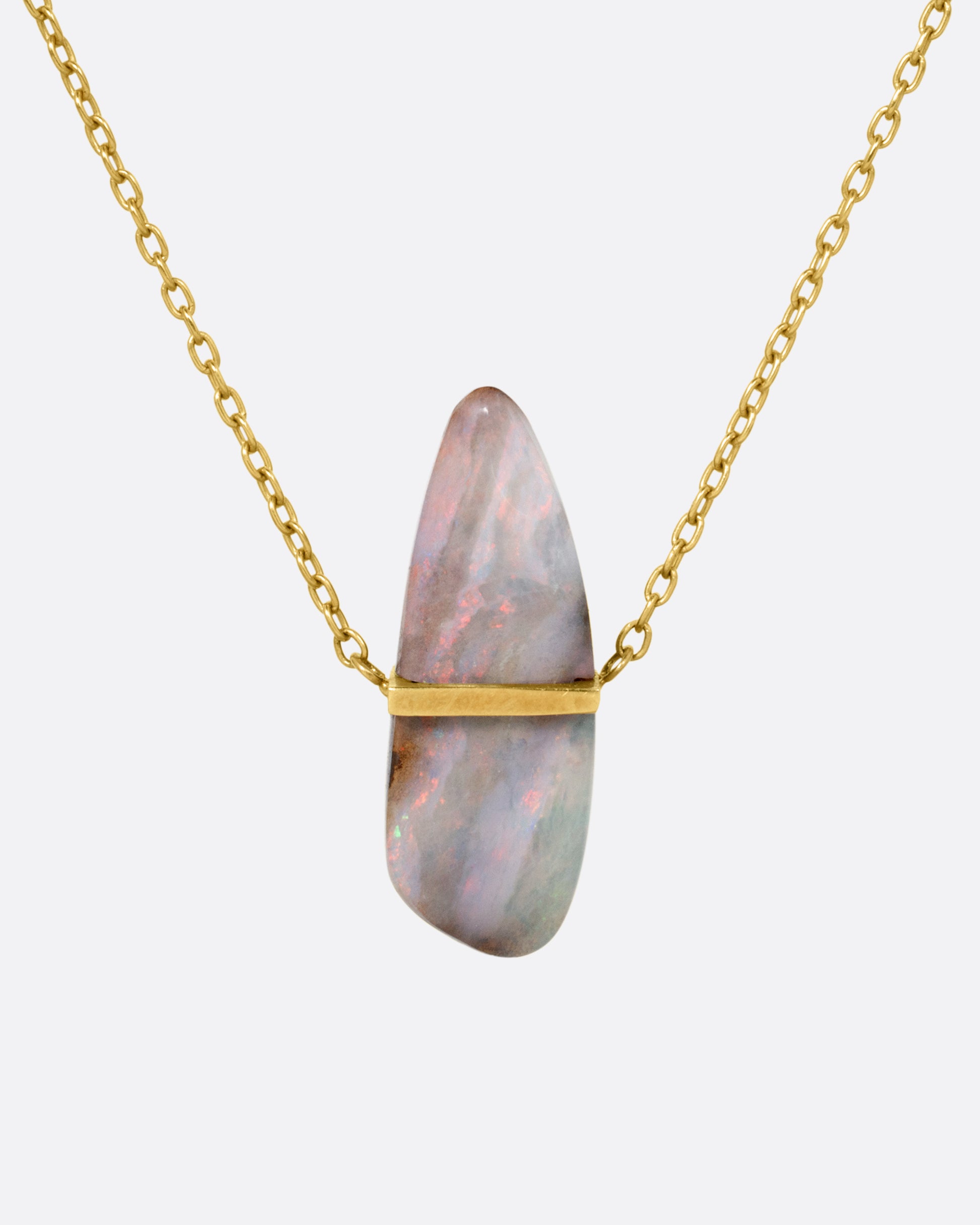 A yellow gold necklace with a freeform opal pendant, shown from the front.