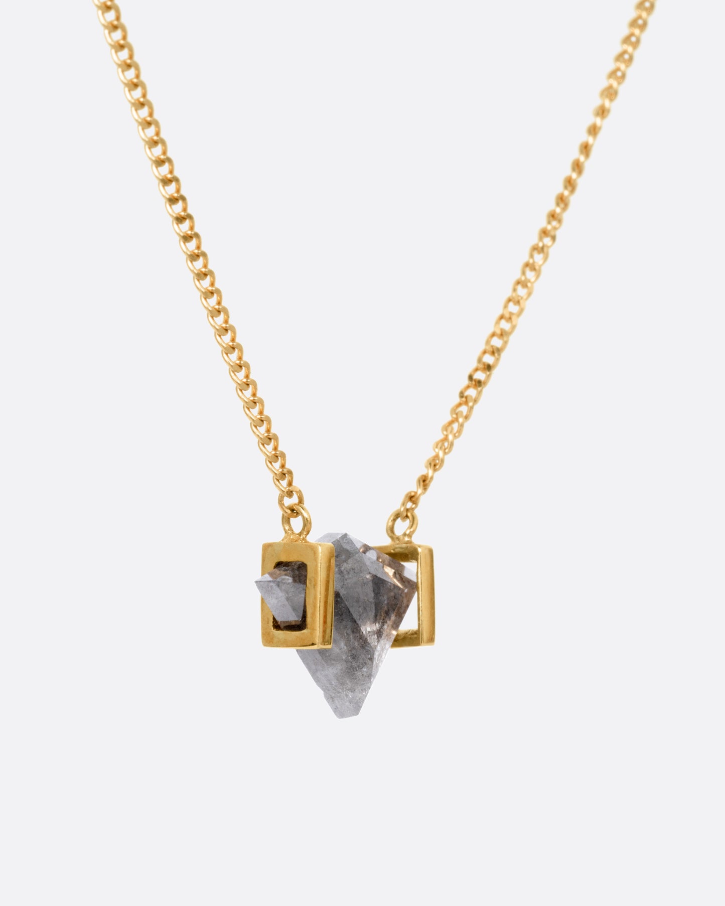 A yellow gold necklace with a salt and pepper diamond pendant, shown from the side.