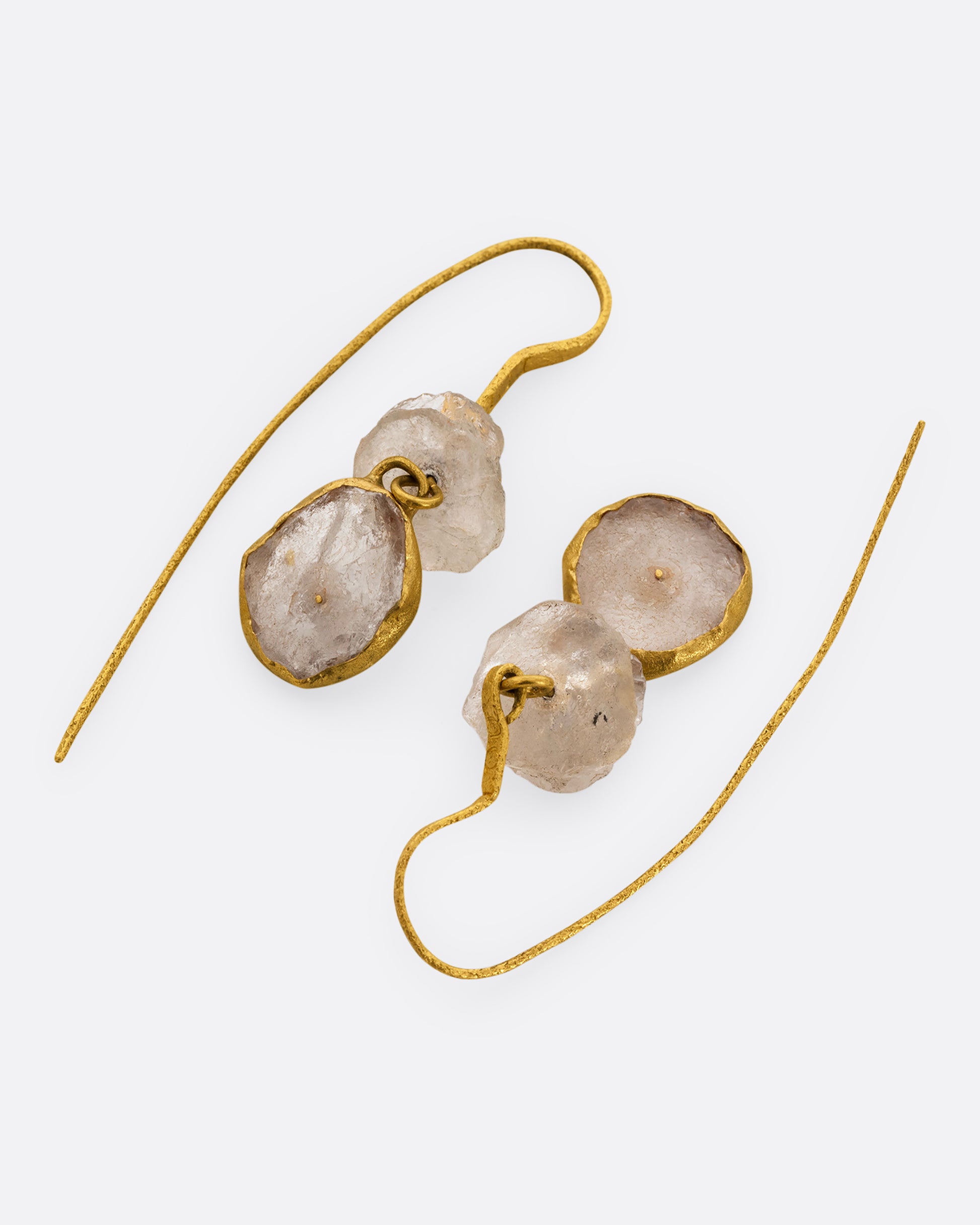 A pair of earrings with white quartz stacks, yellow gold ear hooks, and two front- facing gold wrapped quartz slices. Shown from the front.