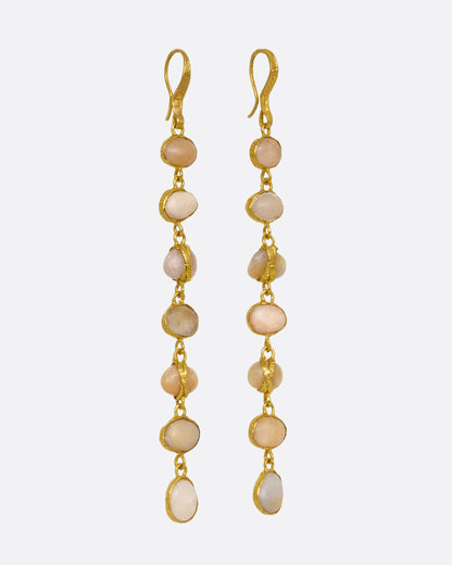 A pair of earrings with even river pebbles, each wrapped in yellow gold hanging from yellow gold ear wires. Shown from the side.