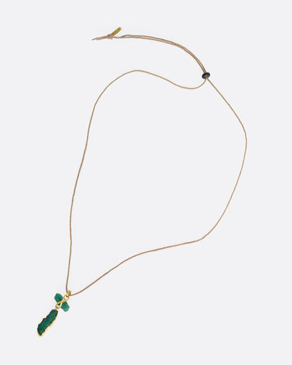 A high karat yellow gold necklace with an two raw emeralds on a cord. Shown laying flat.