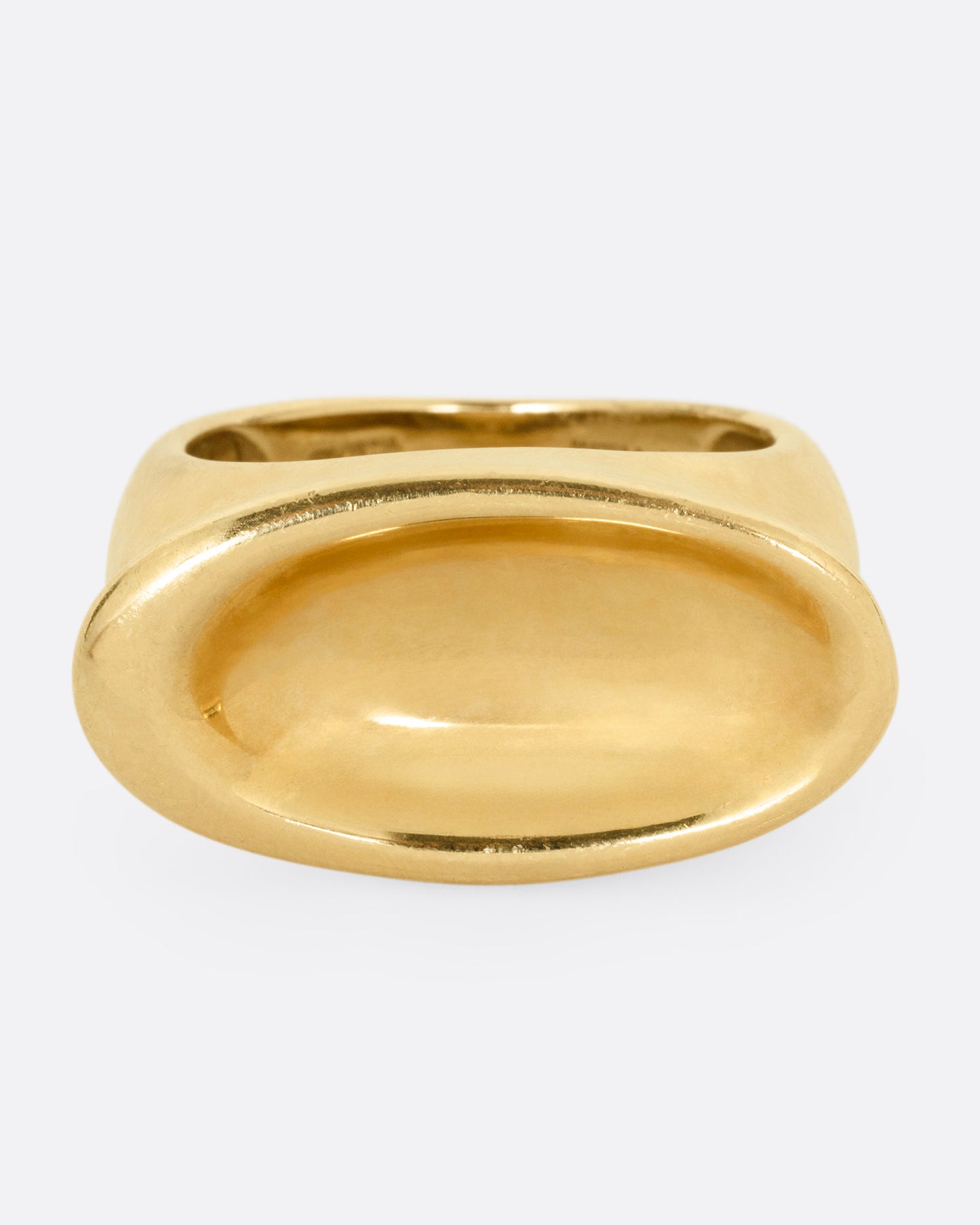 A yellow gold ring with a broad oval signet with a slight concave, shown from the front.