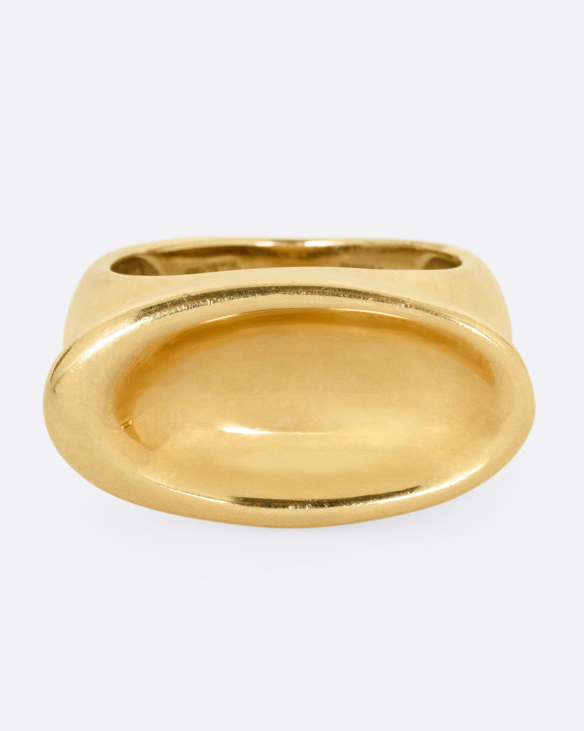 A yellow gold ring with a broad oval signet with a slight concave, shown from the front.