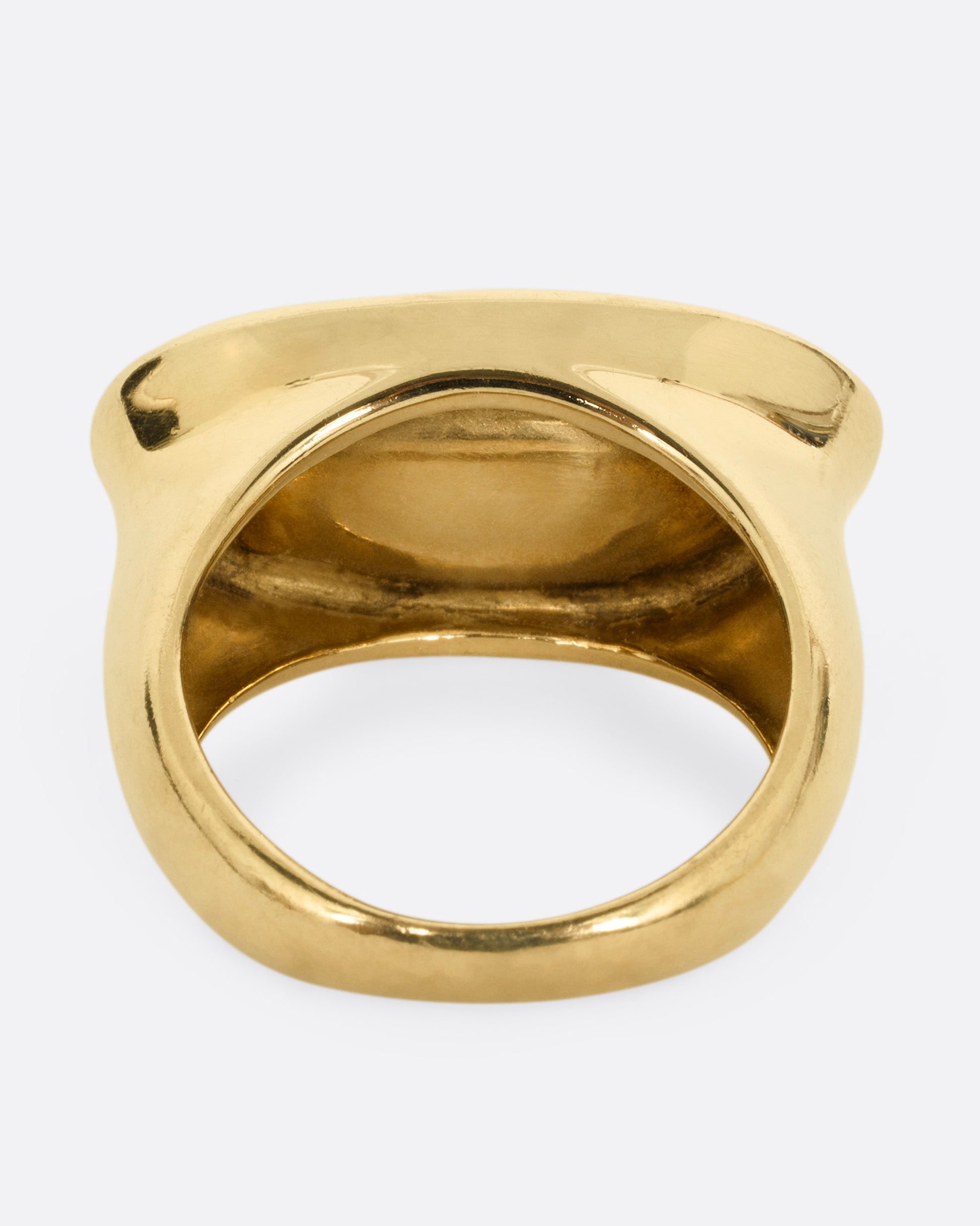 A yellow gold ring with a broad oval signet with a slight concave, shown from the back.