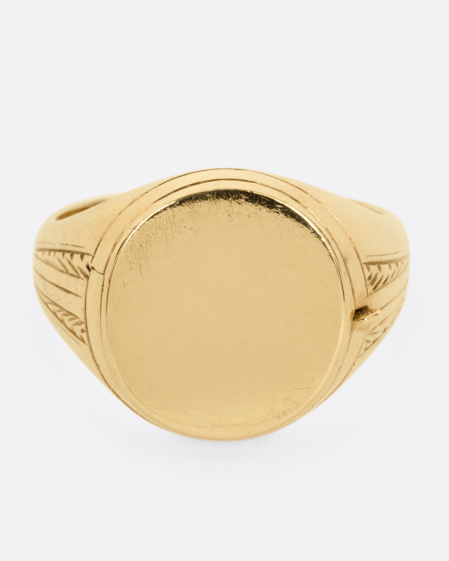 A yellow gold round-faced locket signet ring, shown from the front.