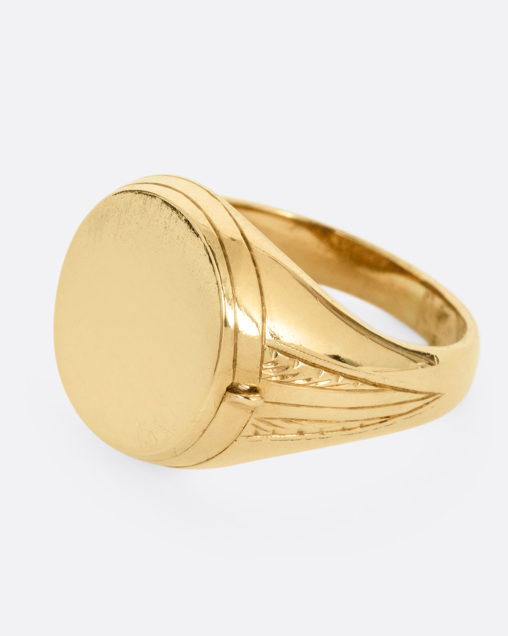 A yellow gold round-faced locket signet ring, shown from the side.