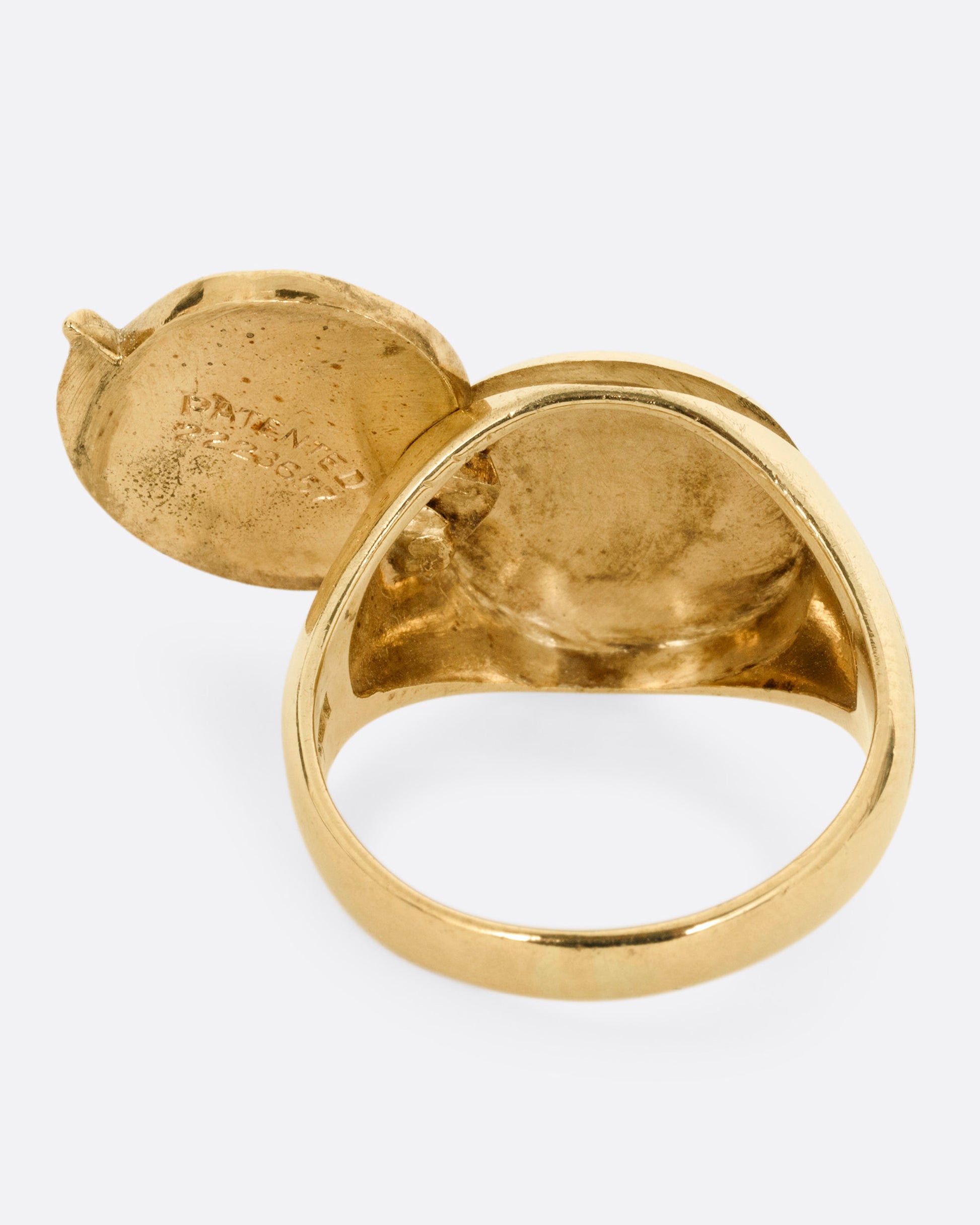A yellow gold round-faced locket signet ring, shown from the back.