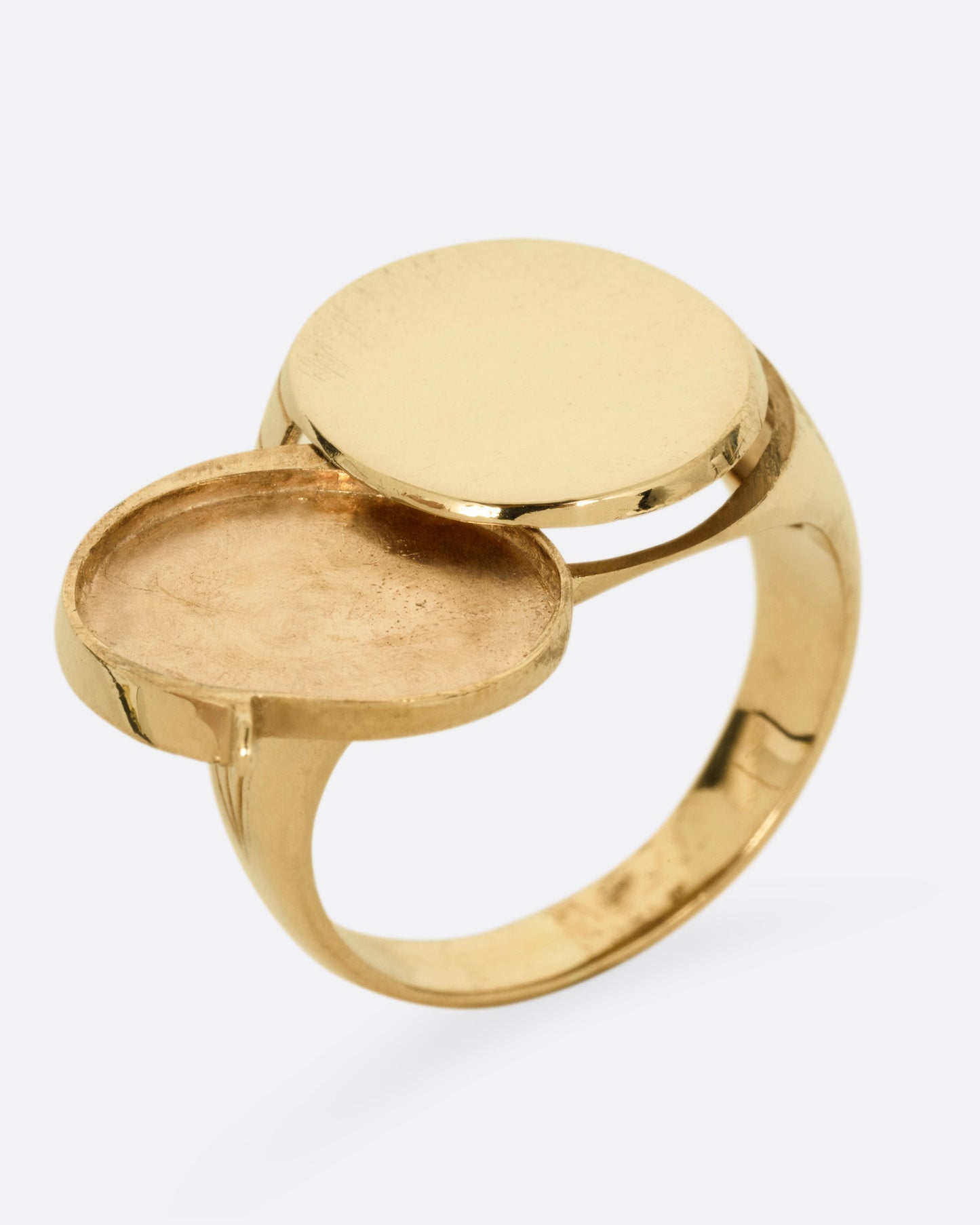 A yellow gold round-faced locket signet ring, shown standing up from the side.