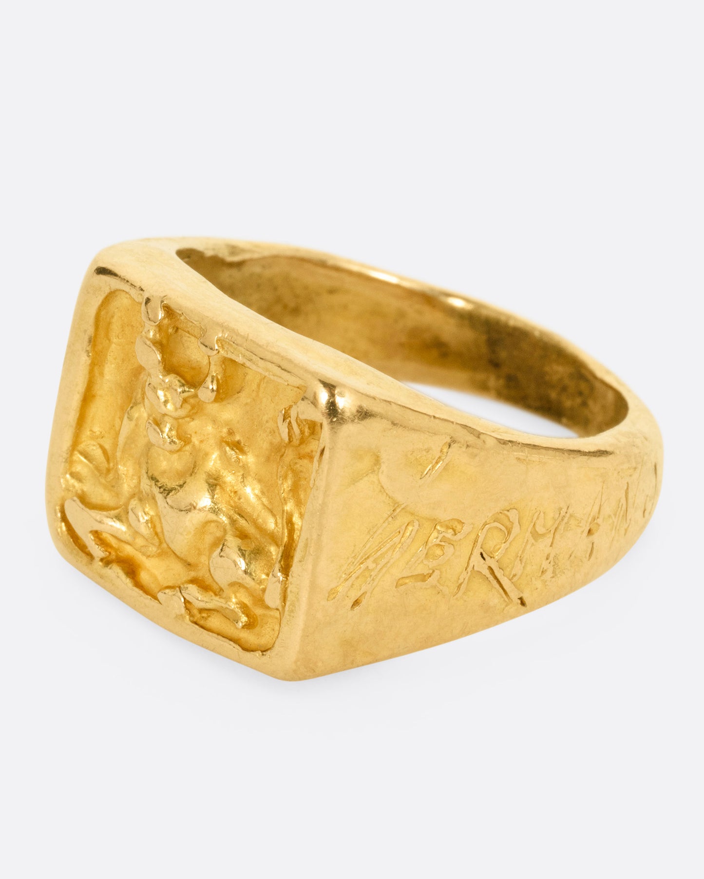 A yellow gold brutalist signet ring with an abstract bull on the front and 'hermano' scrawled on its shoulder, shown from the side.