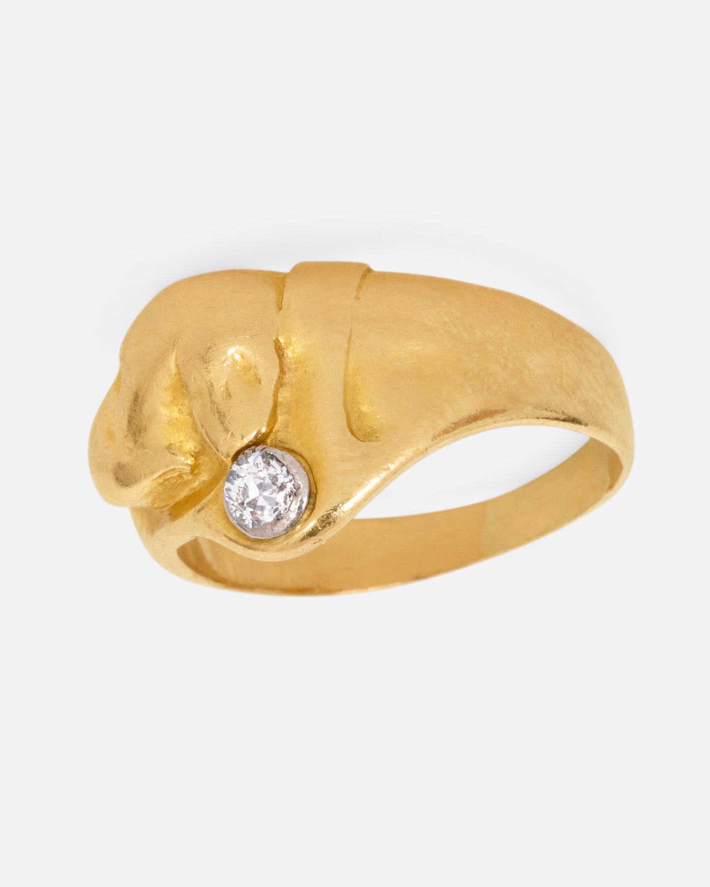 A yellow gold ring with the profile of a dog and a single diamond. Shown from the side.