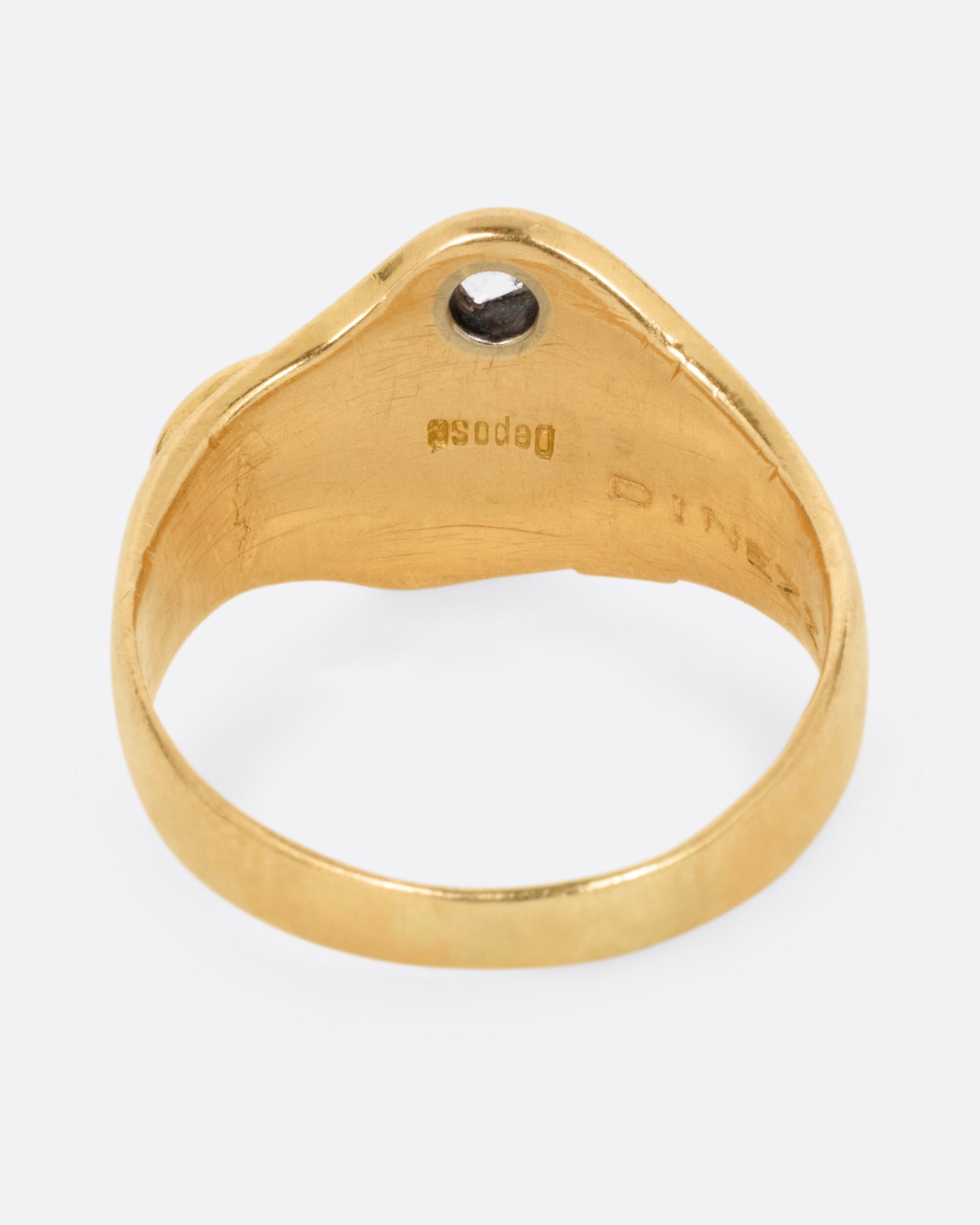 A yellow gold ring with the profile of a dog and a single diamond. Shown from the back.