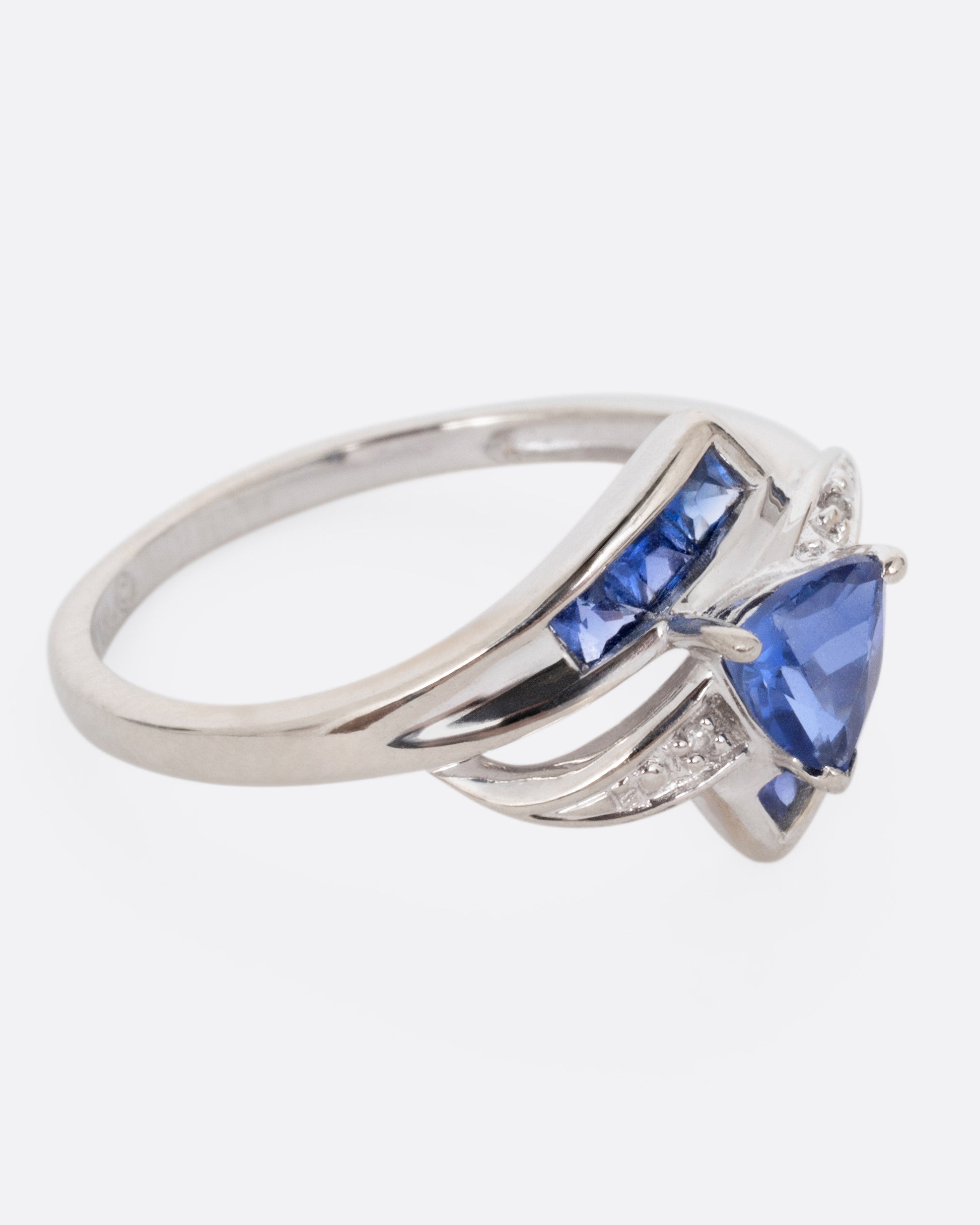 A white gold wrap wring with diamonds and sapphires, shown from the side.