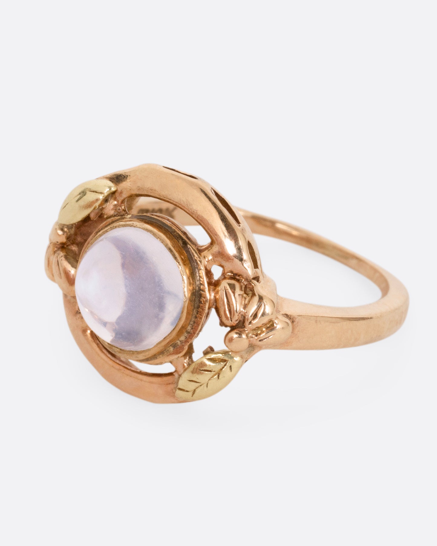 A rose and yellow gold moonstone cabachon ring, shown from the side.
