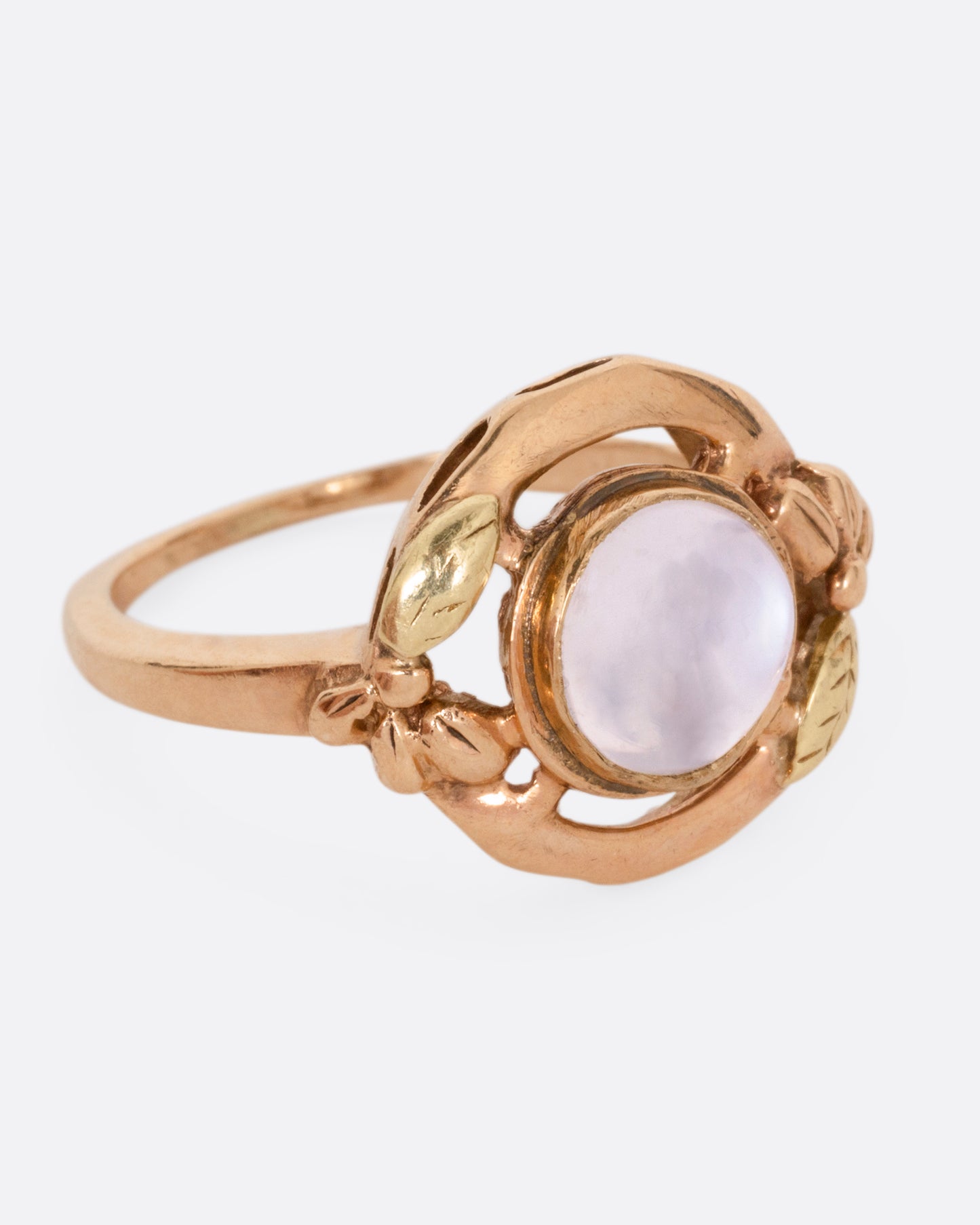 A rose and yellow gold moonstone cabachon ring, shown from the side.
